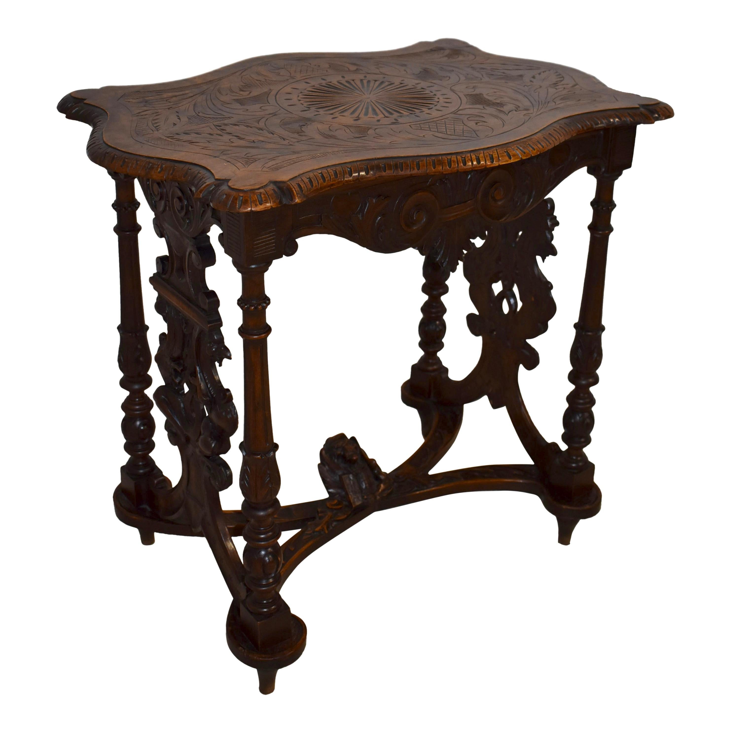 Hand-carved from European oak, this handsome table features a carved scalloped top raised on four turned legs with side carvings uniting the side legs. The lower legs are joined by a curved X stretcher. At the center of the stretcher sits the focal