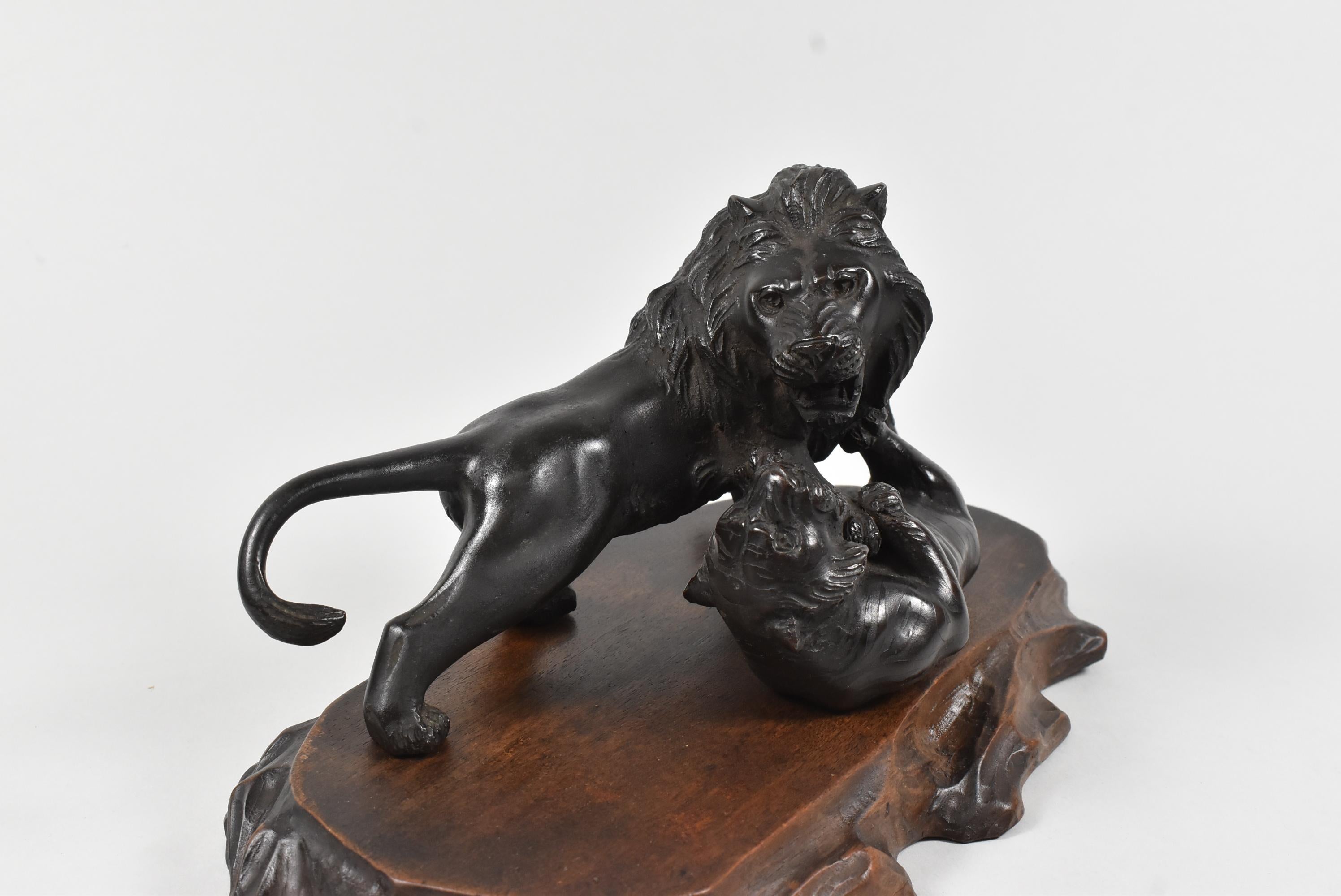 Statue de combat en bronze représentant un lion et un tigre sur une plateforme en bois sculpté. Marque de fabricant asiatique. Très bon état. Dimensions : 4.5