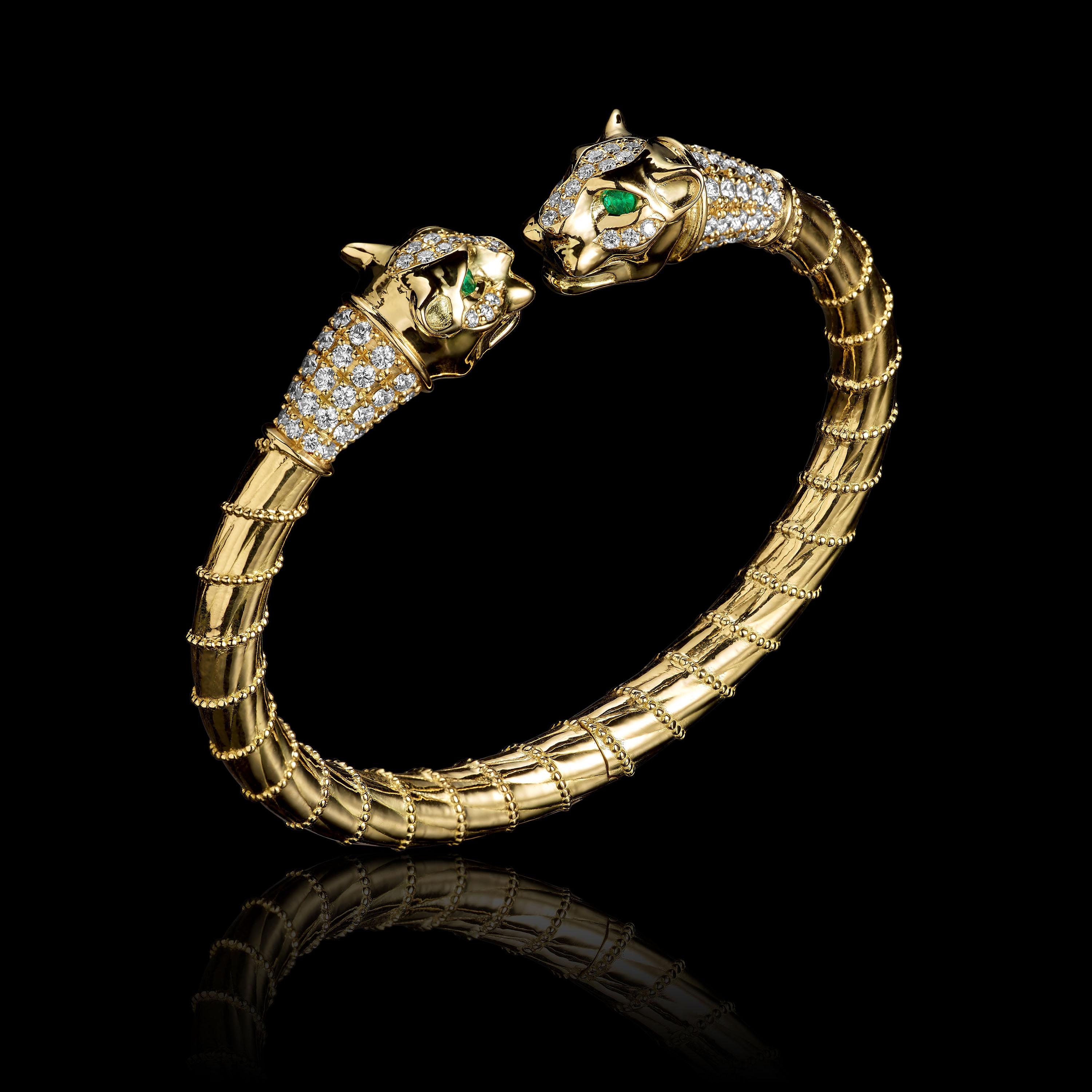 Lioness bracelet in 18K gold, with paved brilliant diamonds, and emeralds eyes. Detailed lioness faces, ornamental gold rope pattern, and hidden spring/hinge mechanism.

This bracelet features two lioness heads with emerald eyes and collars of