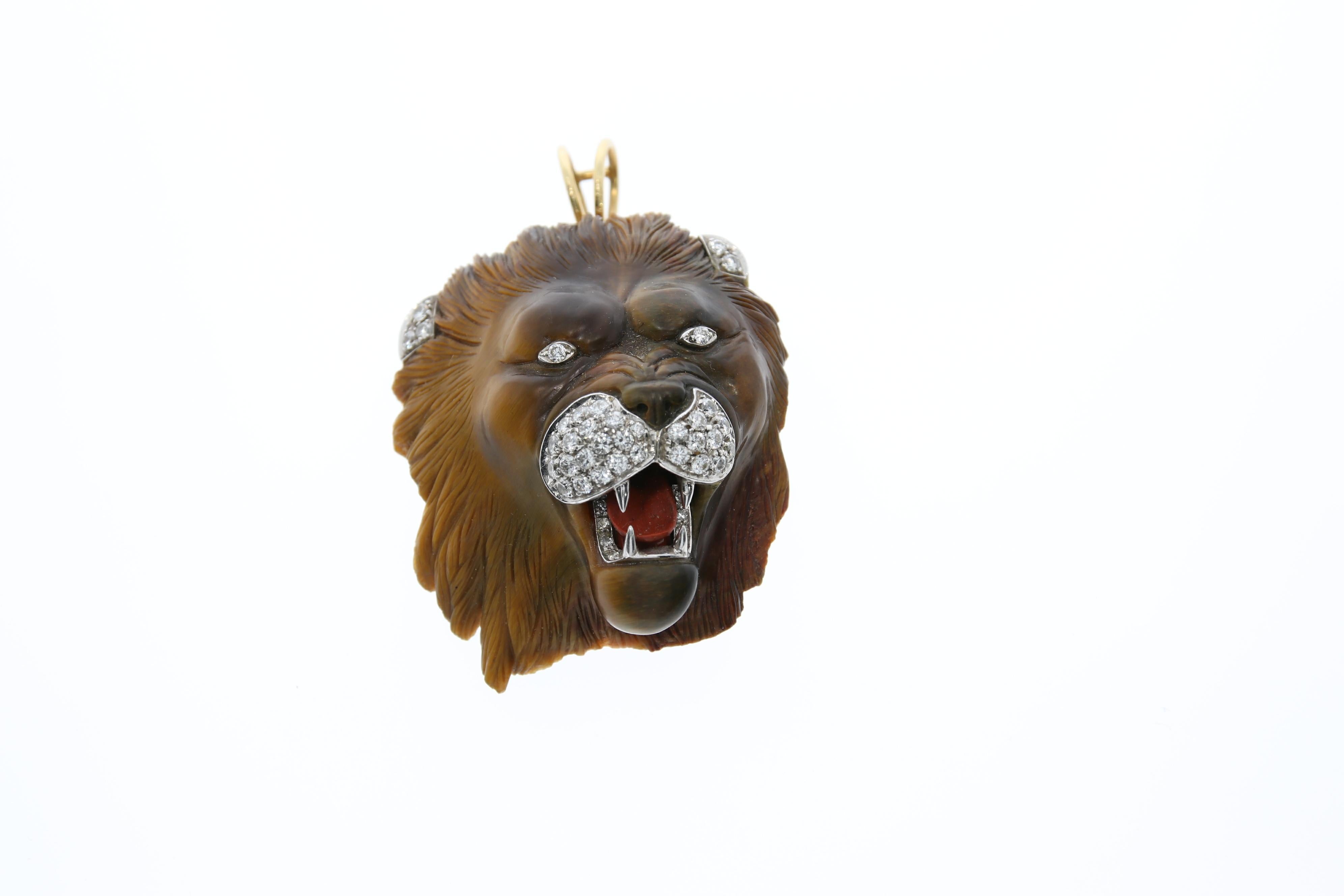 Impressive carved Lion Head Pendant or Brooch clip. It is made of tiger's eye stone in a beautiful color change from gold to dark brown. Eyes, ears and snout are made of Brilliants pavé set in platinum. 42 Brilliant with circa 1.30 ct. The tongue is