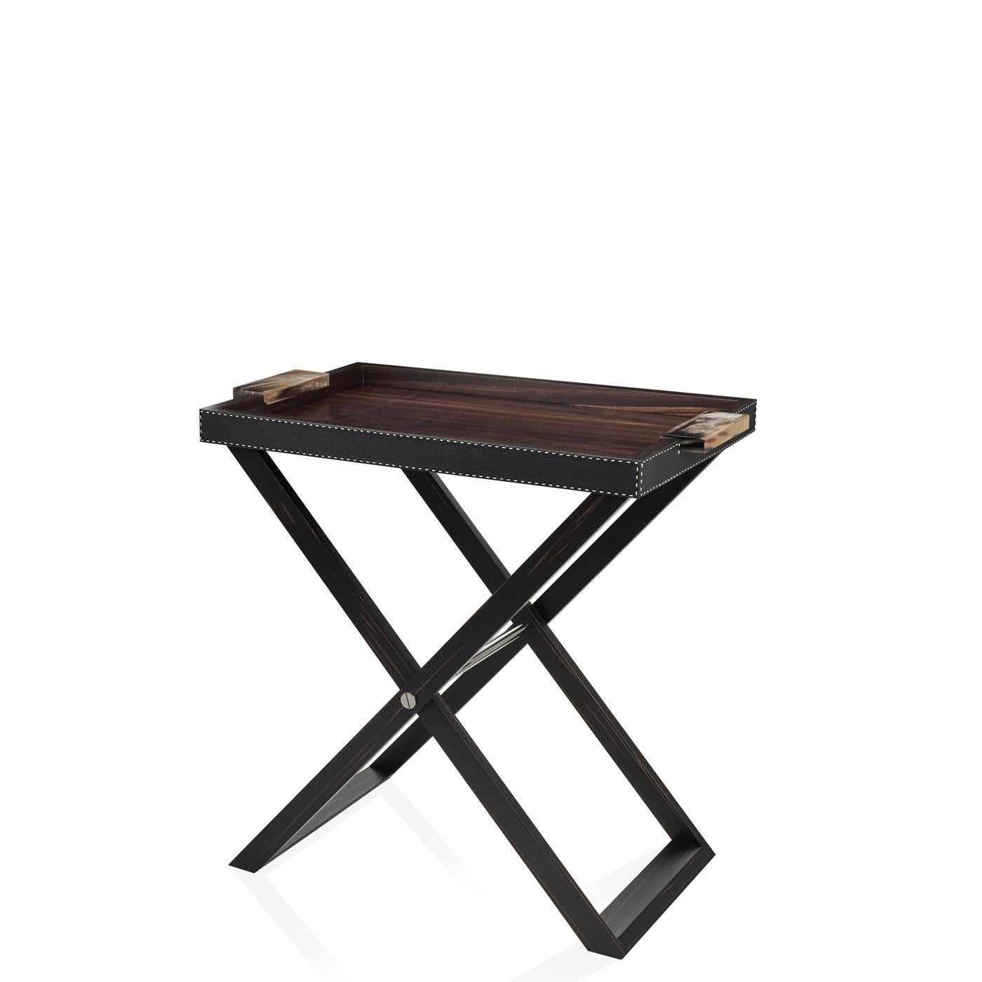 Versatile and elegant, Lipari is a butler’s tray that can be used both for serving drinks and as an extension of the side table. The tray in matte Amara ebony veneer and Aida pebbled leather, Onyx colour rests on a folding structure in wood. The