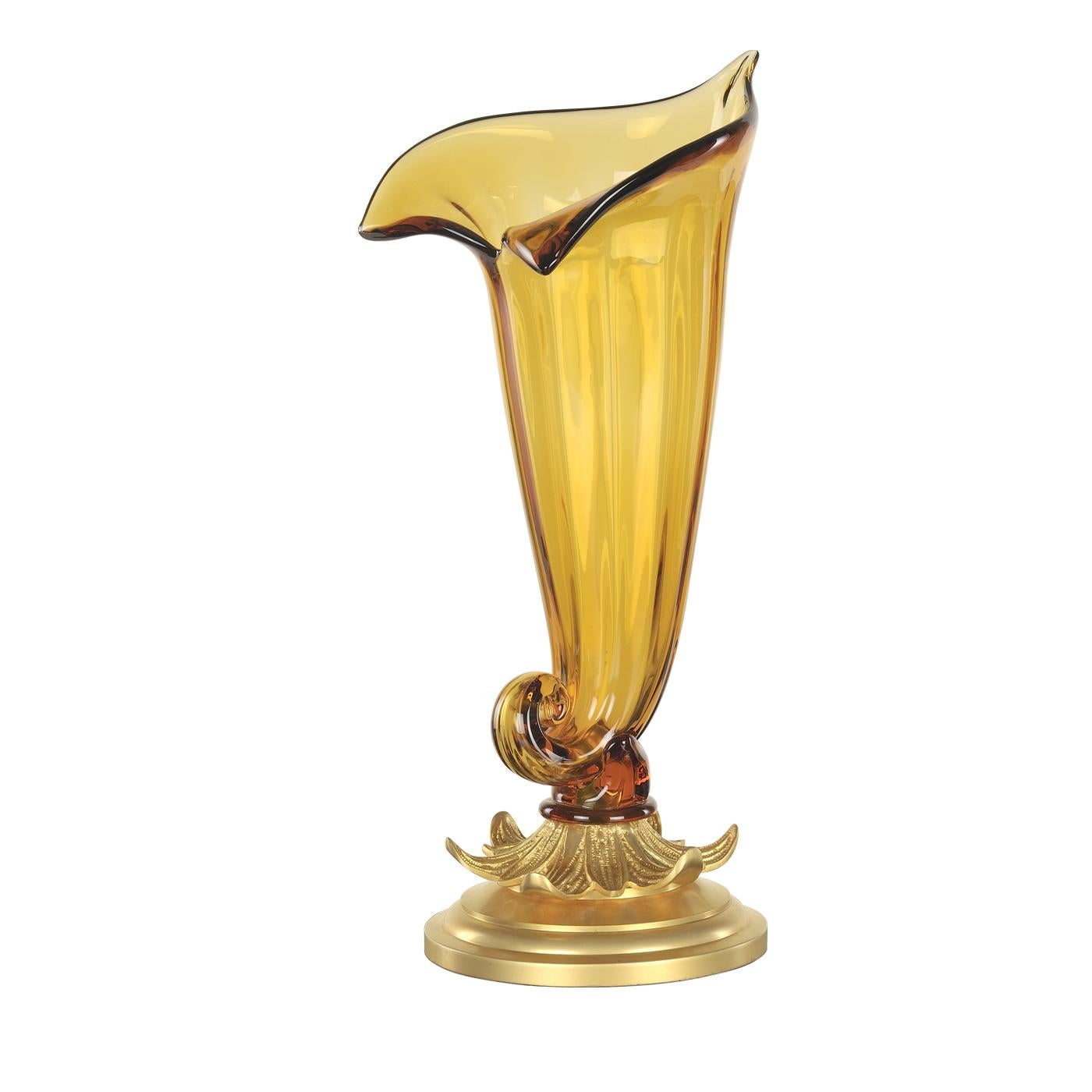 This striking vase rests on an exquisite bronze base with a satin gold finish. The body is in polished crystal with an amber color and depicts a zantedeschia, a flower known since Greek mythology and celebrated in poetry and painting. Its slender