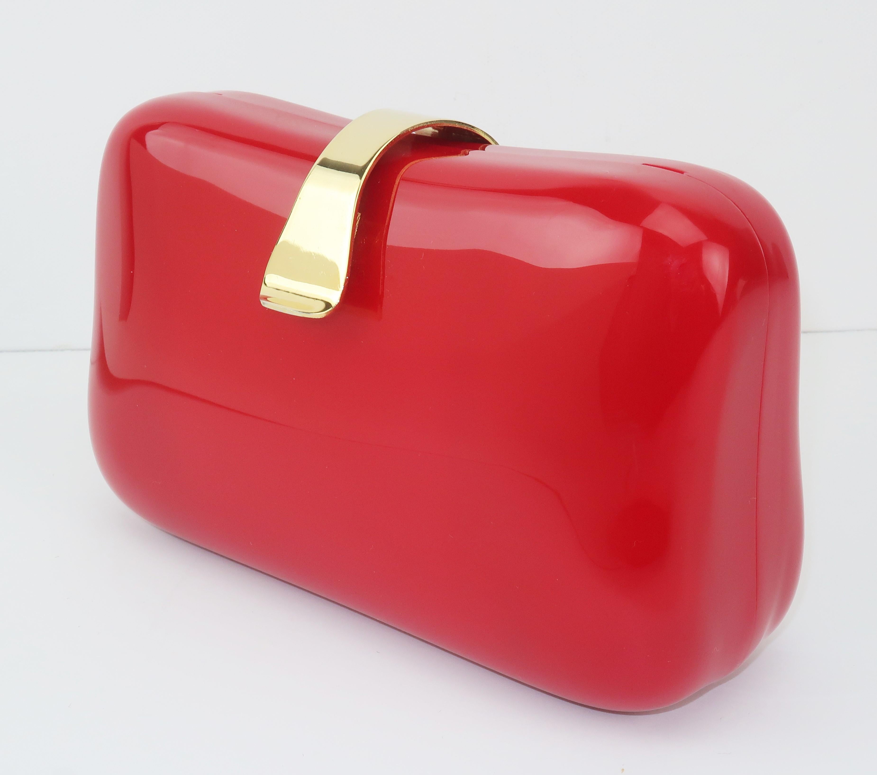 A 1980's lipstick red lucite handbag in a fun little box shape with a flip lock closure.  It sports a gold chain drop-in shoulder strap handle and features a red faille fabric lined interior with an open pocket.  As pretty to display as to carry! 