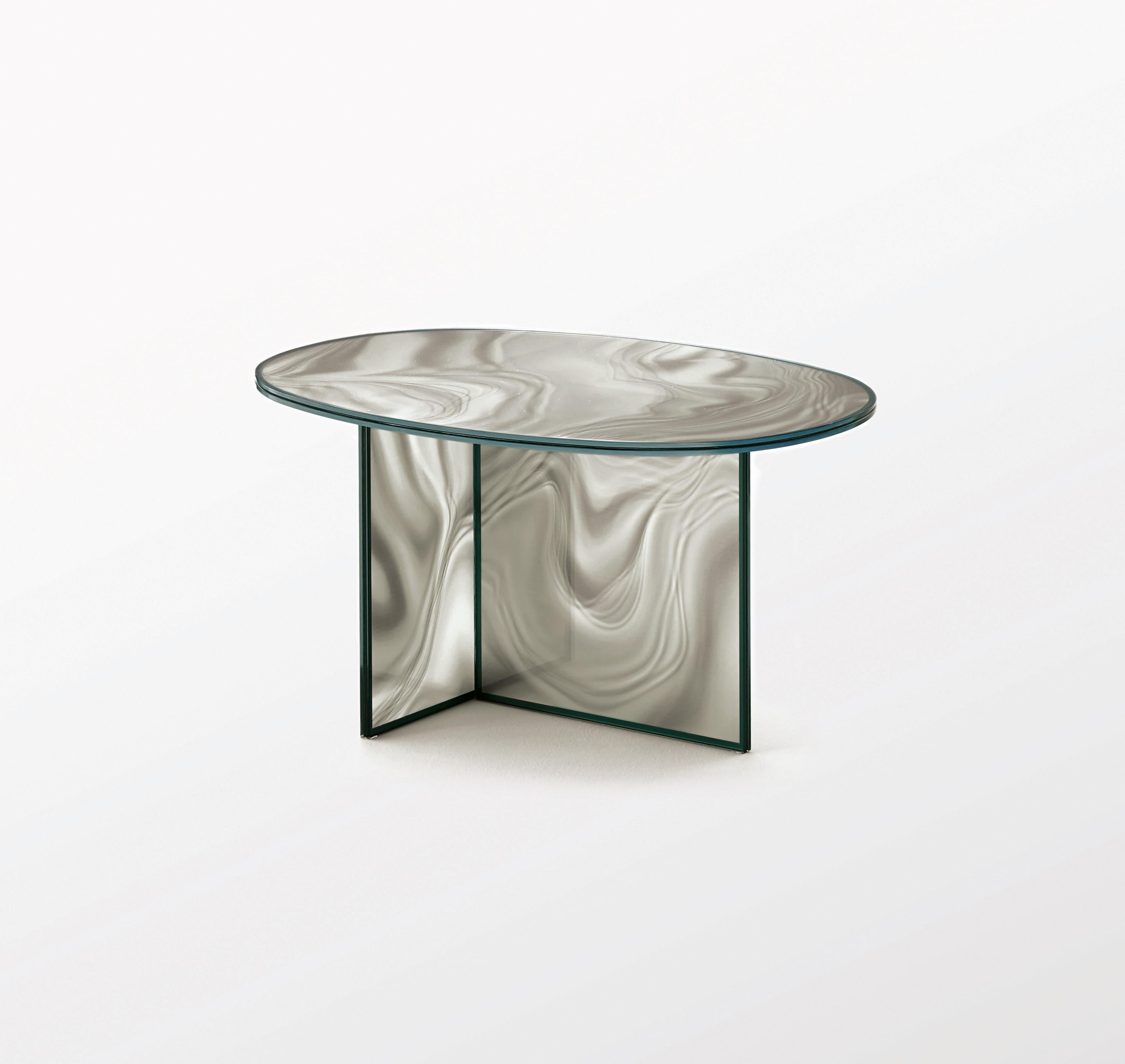 High and low oval-shaped tables in tempered extra light glass, with faded and irregular decoration which takes on the color and veins of marble.
The surprising image changing effect makes the veining look dynamic and variable depending on the