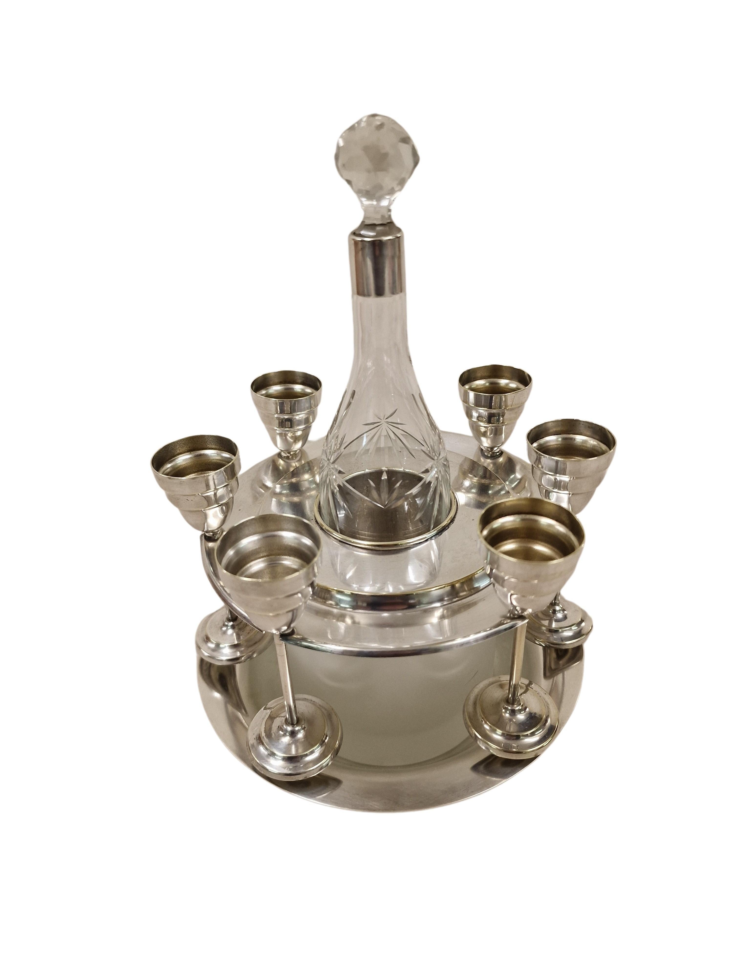 Wonderful, highly decorative liqueur set, made by the well-known German manufacturer WMF - Würtembergische Metallwarenfabrik, in the 1930s.

The set consits of a bottle, 6 small cups and a base with a cooler system, all made in elaborate design. The