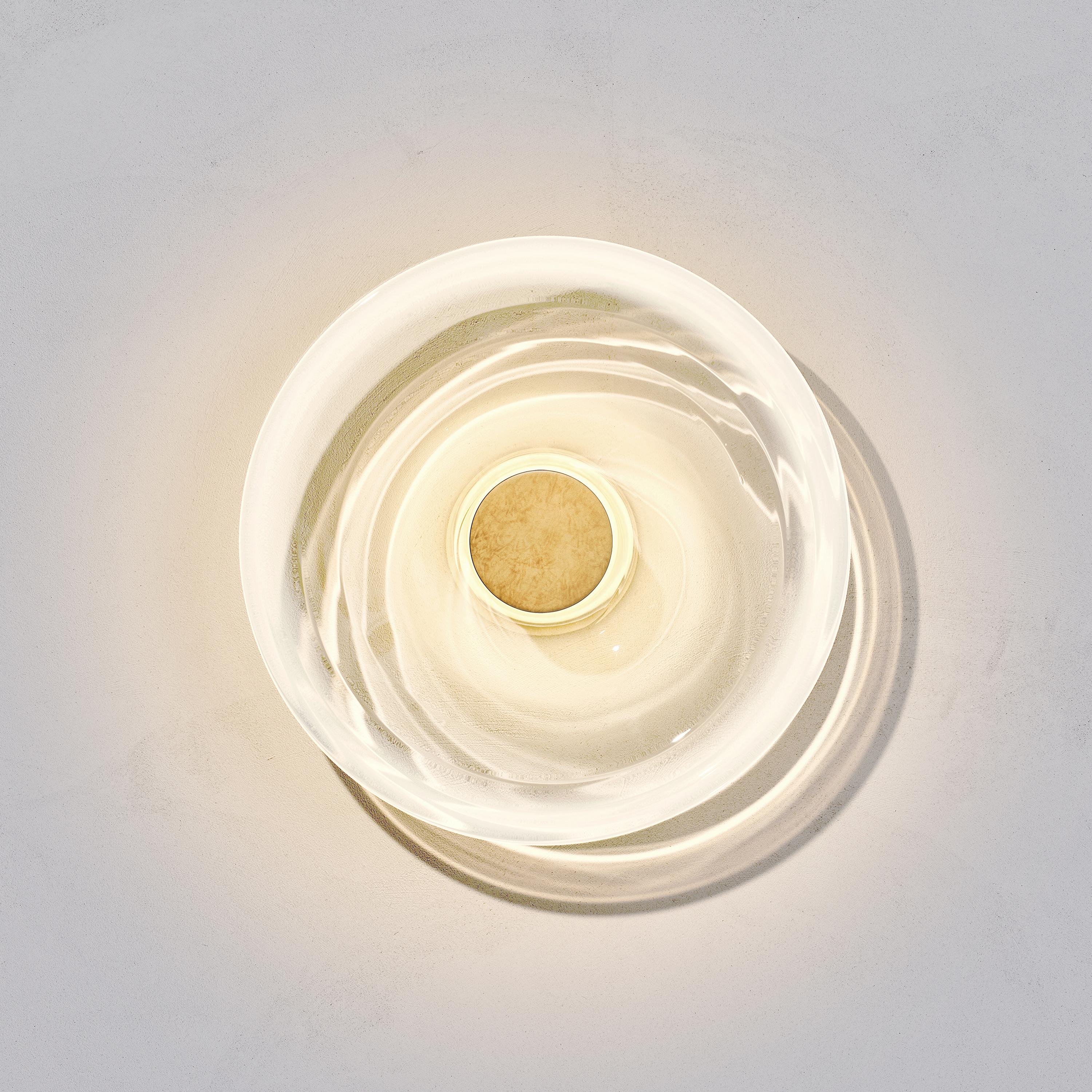 Liquid Alabaster wall light is designed by international illumination artist Eva Menz. Inspired by the circular ripples and reflections created on water, the white gradient glass is transformed into a beautiful sculptural sconce.

Each piece is