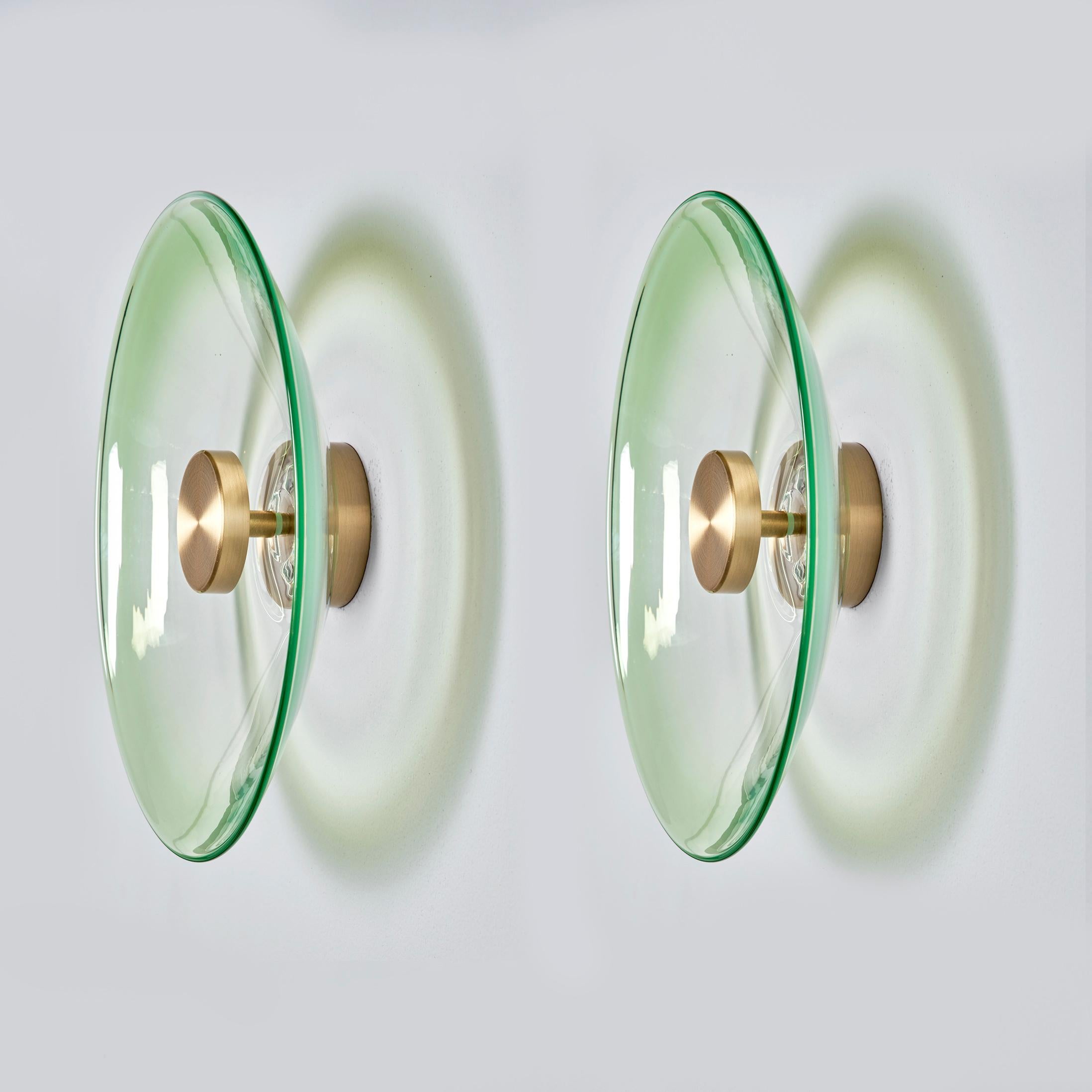 Unique opportunity to get your hands on a pair of the Liquid Jade wall lights designed by international illumination artist Eva Menz. Inspired by the circular ripples and reflections created on water. The hand blown glass with a gradient green