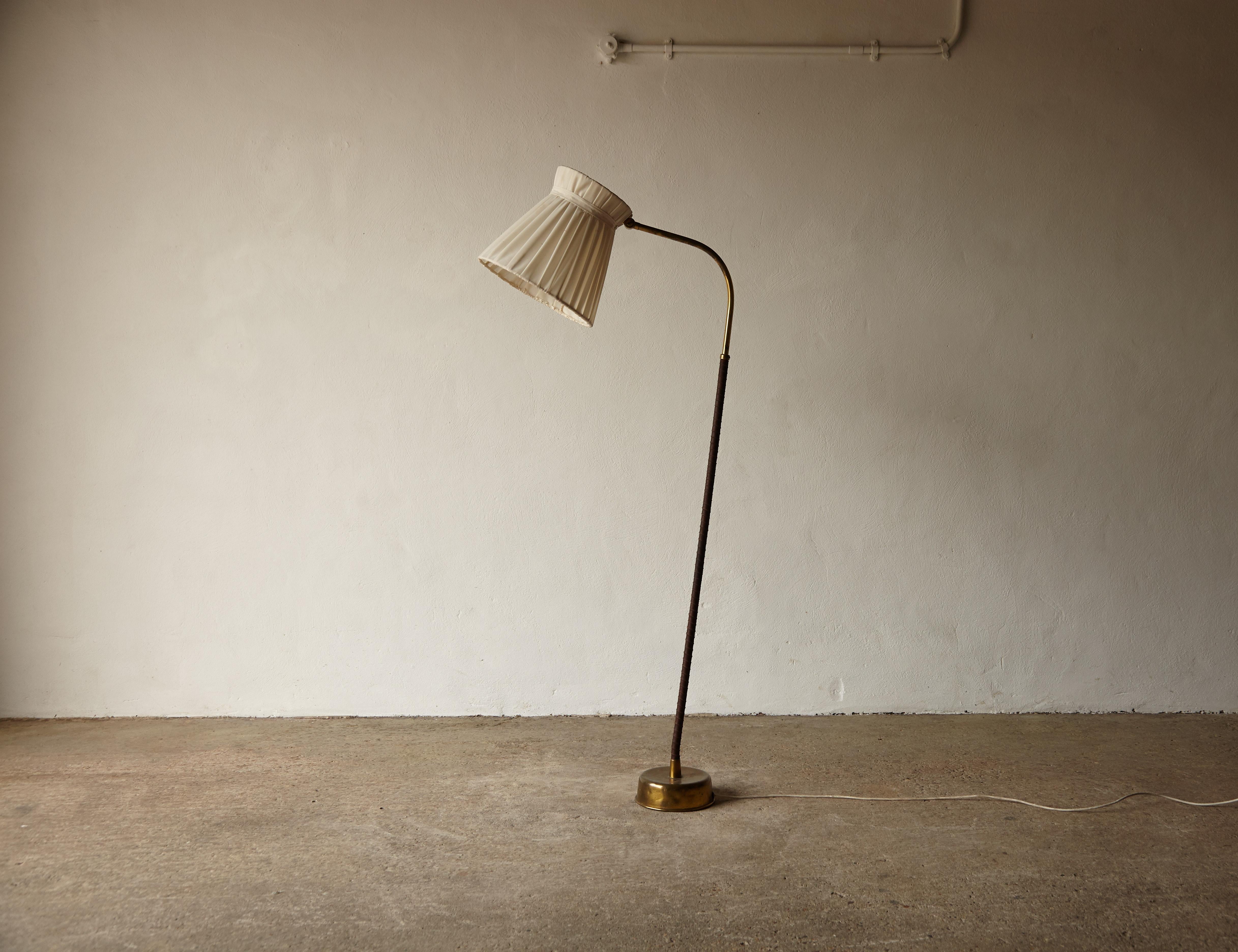 Original Lisa Johansson-Pape Model 2063 floor lamp for Stockmann Orno, Finland, 1950s. The lamp is in original condition, with patina to the brass, the leather stem re-done, and the original shade fabric shows some stains (see photos) so may benefit