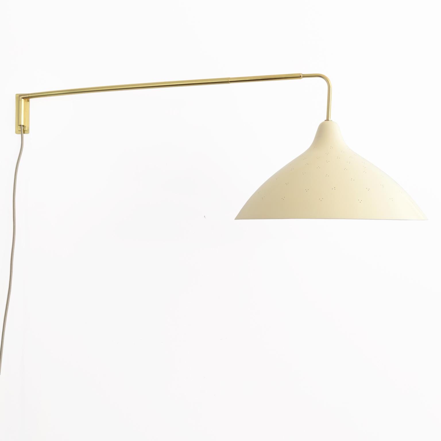 Lisa Johansson-Pape, Scandinavian Modern wall mounted swing arm lamp with pierced lacquered metal shade and extendable arm. Newly restored, re-polished and lacquered brass, newly lacquered aluminum shade in cream., wired for the USA with one