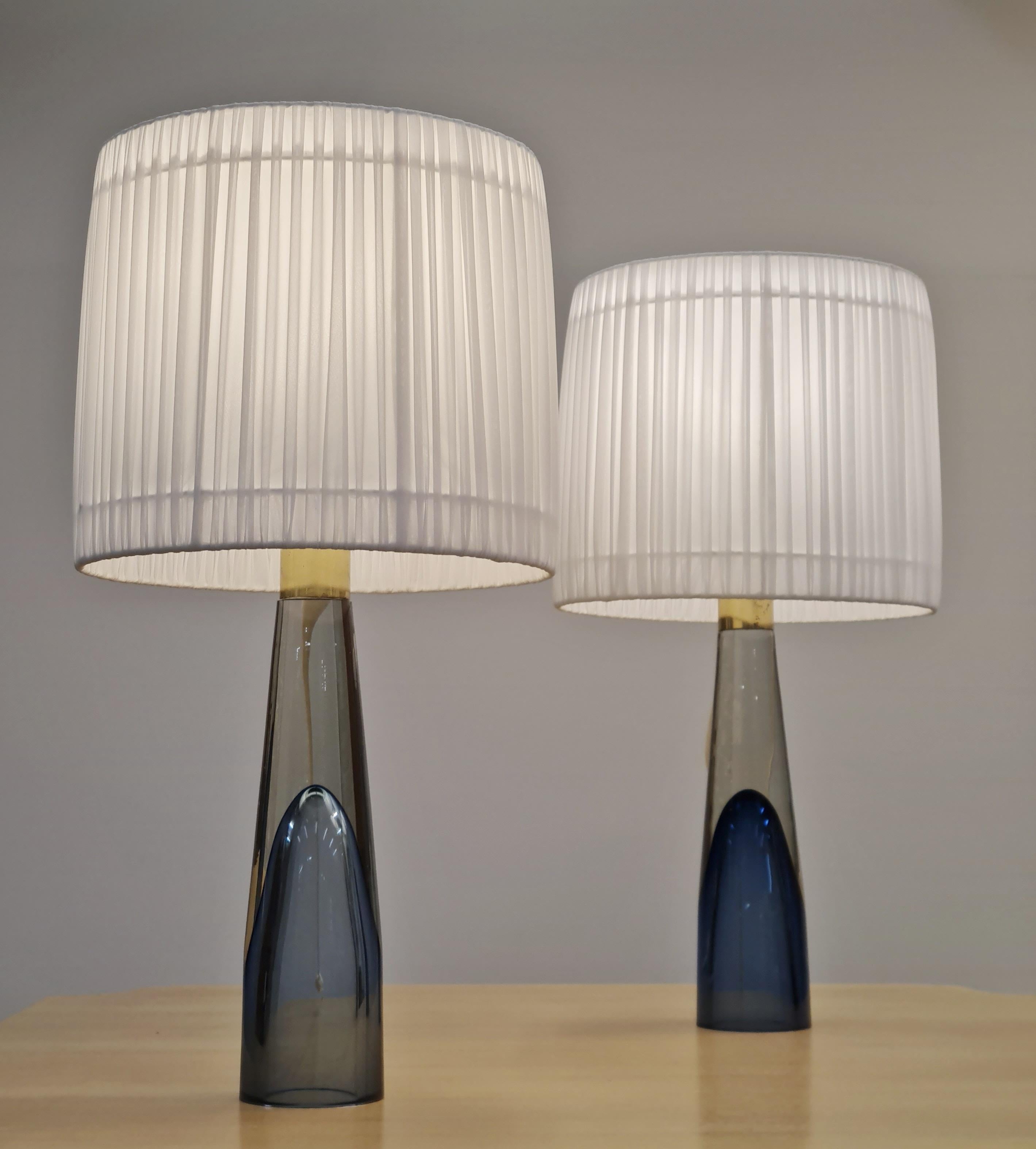 These lamps can be bought as a pair or individually, and even though they aren't an exact match they go perfectly together. Both lamps are exceedingly beautiful with see through art glass legs with a dark blue color within. One of the finest works