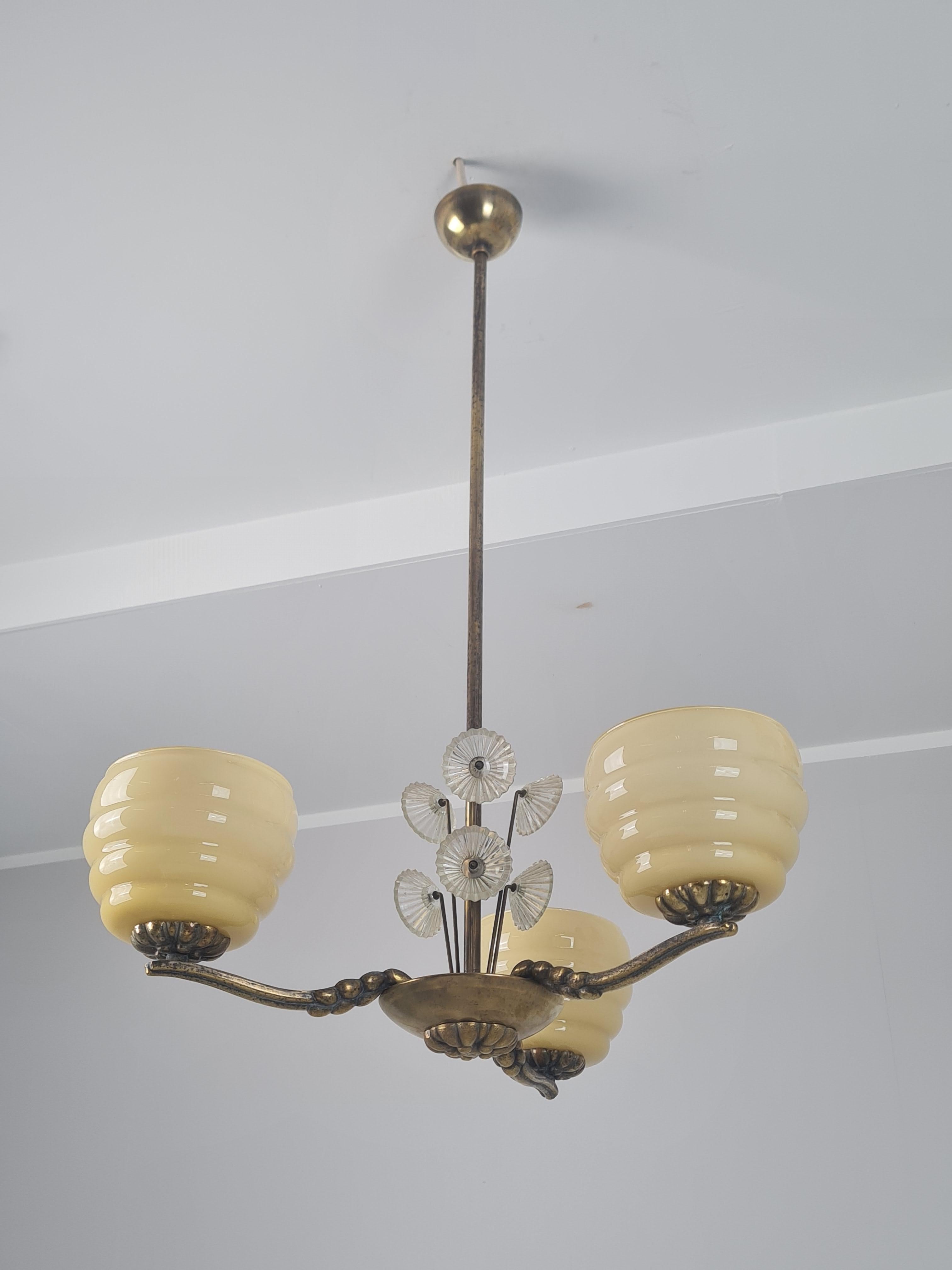 Un pendente decorativo da soffitto in stile Art Déco della celebre designer finlandese Lisa Johansson-Pape. Questo splendido apparecchio a tre bracci è caratterizzato da bracci scultorei in ottone patinato, che mostrano una miscela di metallo ruvido
