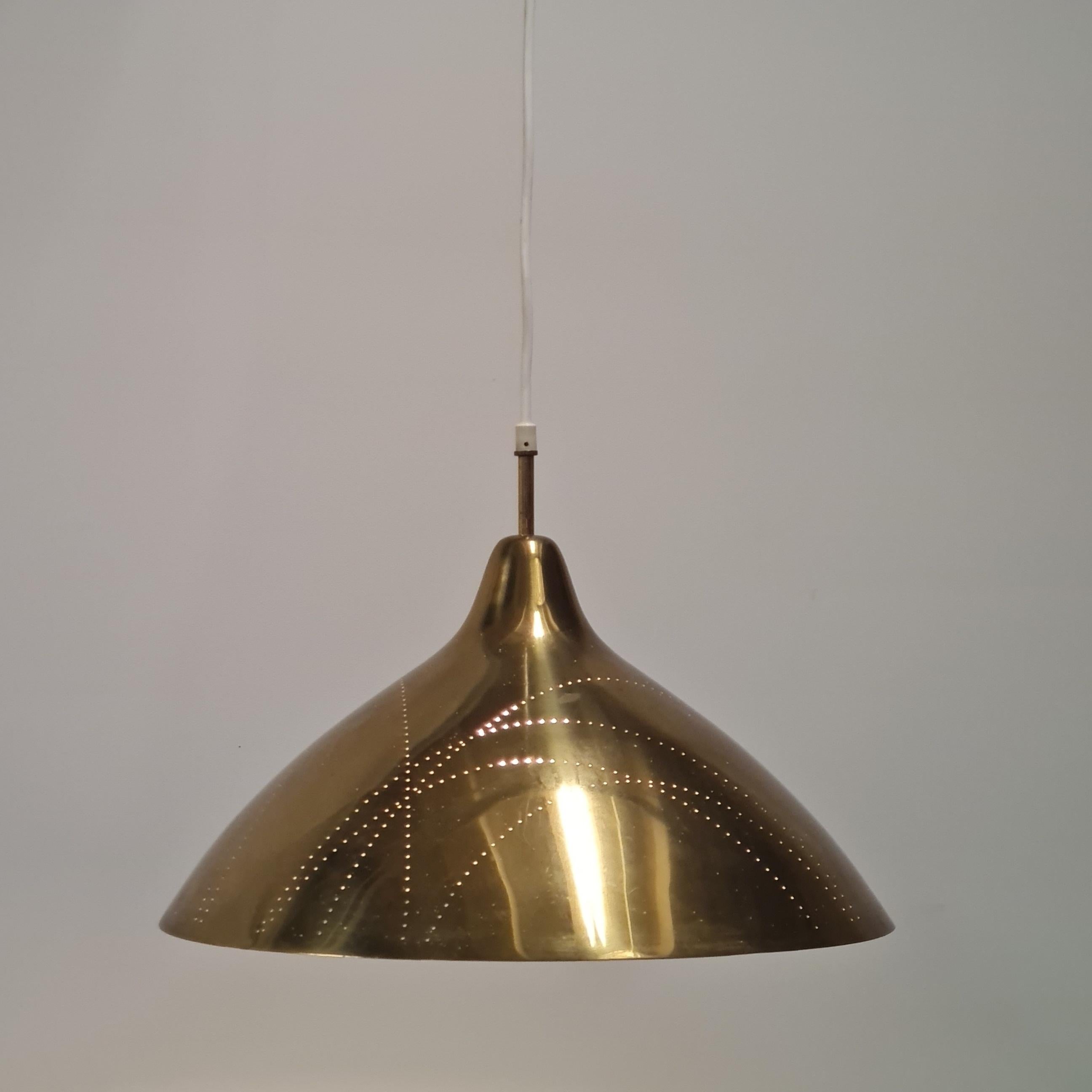 A very beautiful ceiling lamp designed by the genius Lisa Johansson-Pape, and manufactured by Orno in the 1950s. This lamp is in full brass with a perforated shade full of tiny dots that form a lovely design across the lamp. When the lights are