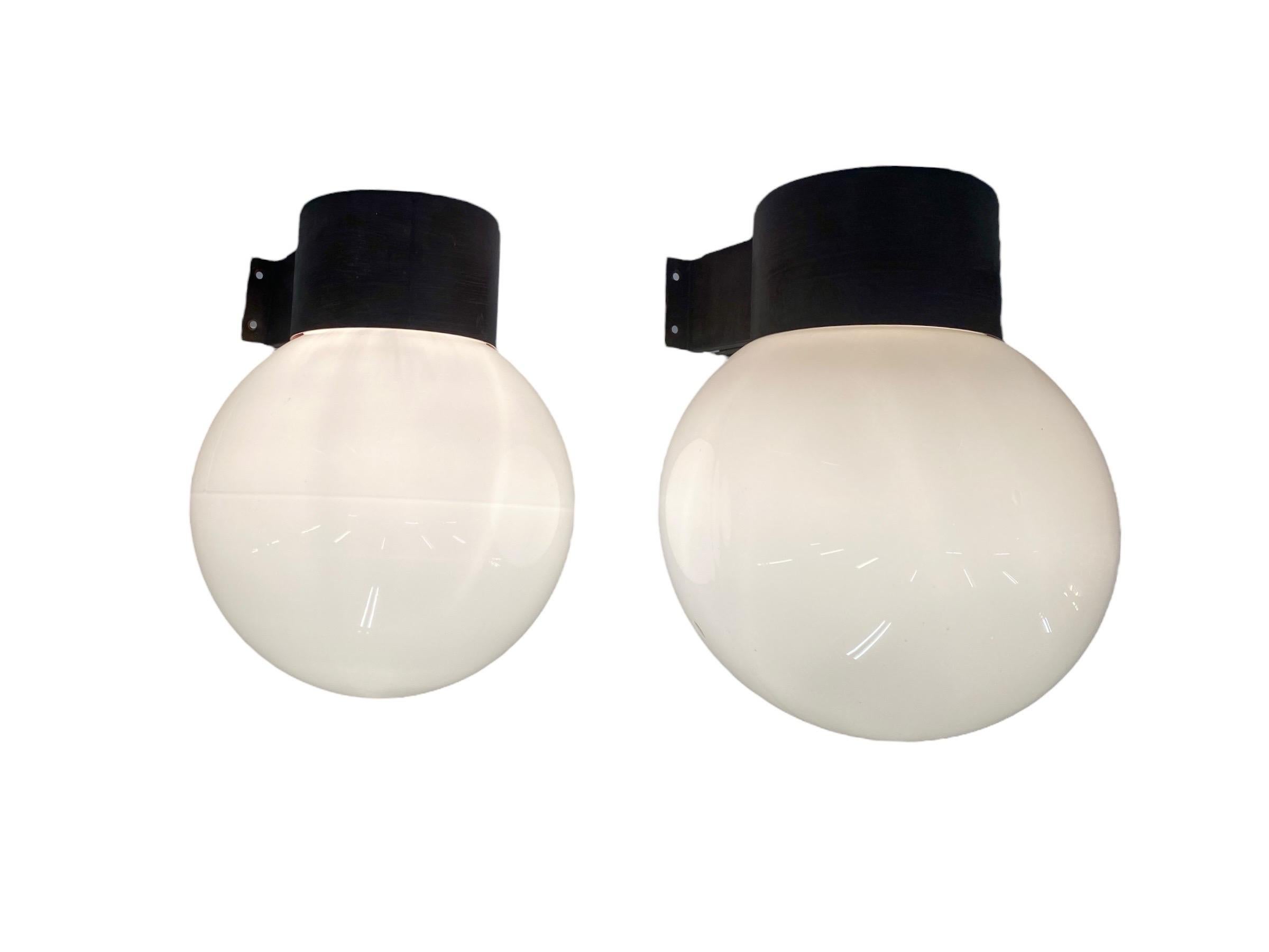 A pair of elegant wall mounted lamps model 17-037, designed by Lisa Johansson-Pape and manufactured by Orno Oy in Finland in the 1960s. Each lamp features a patinated copper/ metal base with an opaline glass shade. 
They have kind of a cold and