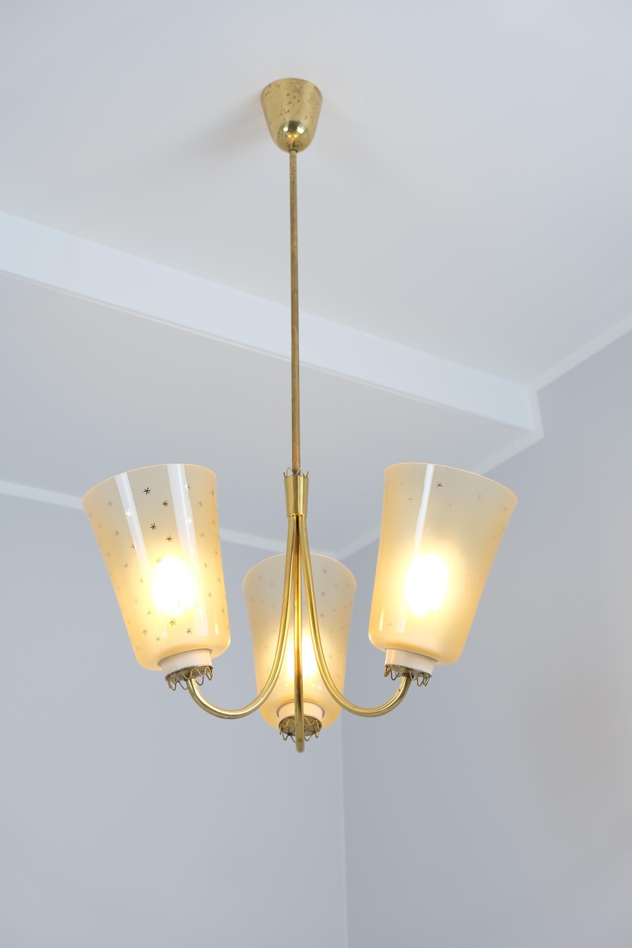 A beautiful and delicate Lisa Johansson-Pape ceiling pendant with hand painted mouth blown glass shades. and spring decorations. The three arm pendant is made of brass and white metal bases for the shades. The lamp shades are mouth blown and have