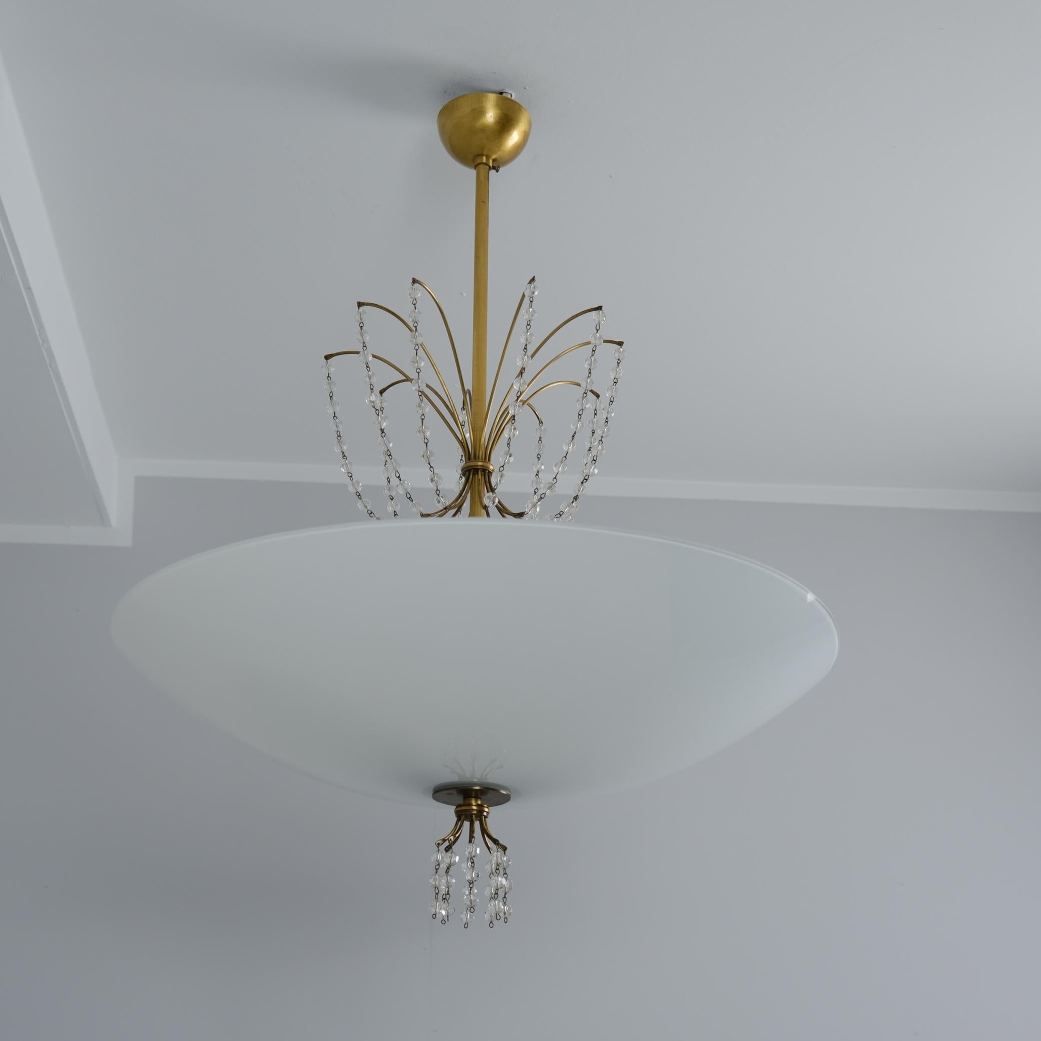 Magnifique plafonnier The Scandinavian Modern Modern, modèle 1068, en laiton, cristal et verre, conçu par Lisa Johansson-Papé et fabriqué par Orno Oy en Finlande dans les années 1940-1950. La lampe présente des cristaux qui pendent comme des gouttes