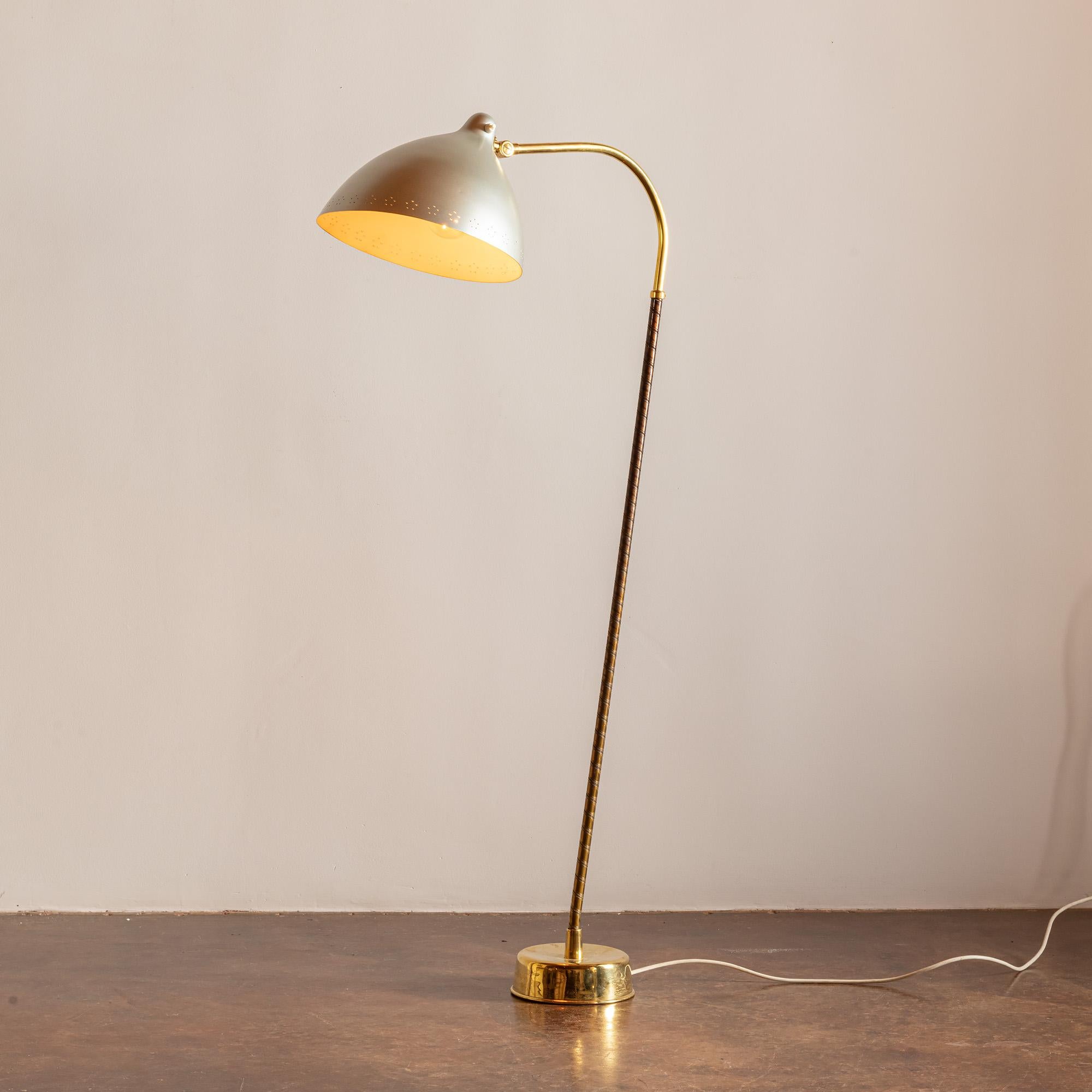 An elegant and rare example of this floor lamp by Finnish designer Lisa Johansson-Pape for Orno in the 1950s. This example with brass shaft and base, and shade in steel. The shaft is wrapped in cognac leather.