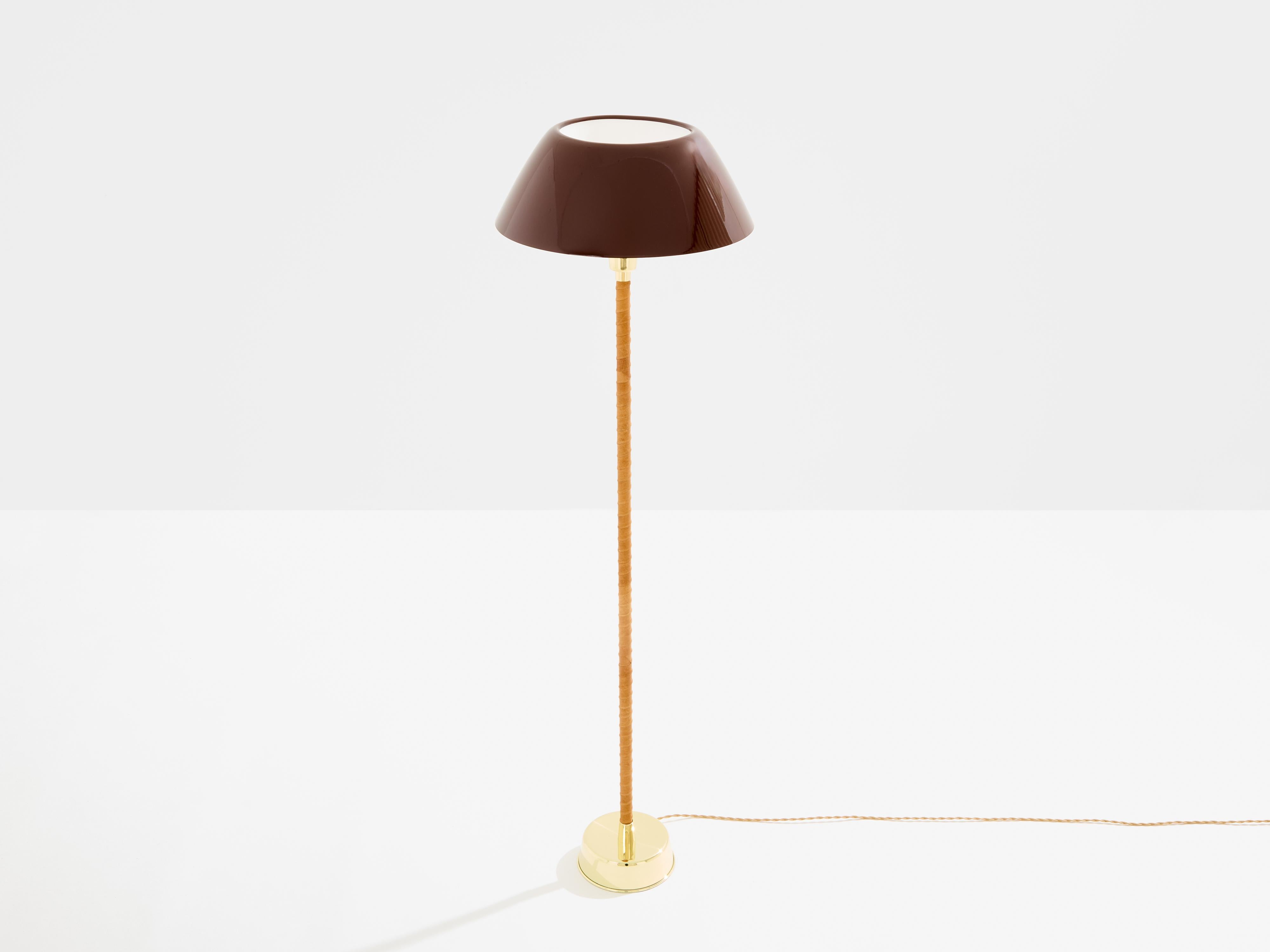 This beautiful floor lamp was designed by Lisa Johansson-Pape for Orno Oy in Finland in 1947. This particular example is a first edition dating from the early 1950s. It features a solid brass base, a stem wrapped with light brown leather, and a warm