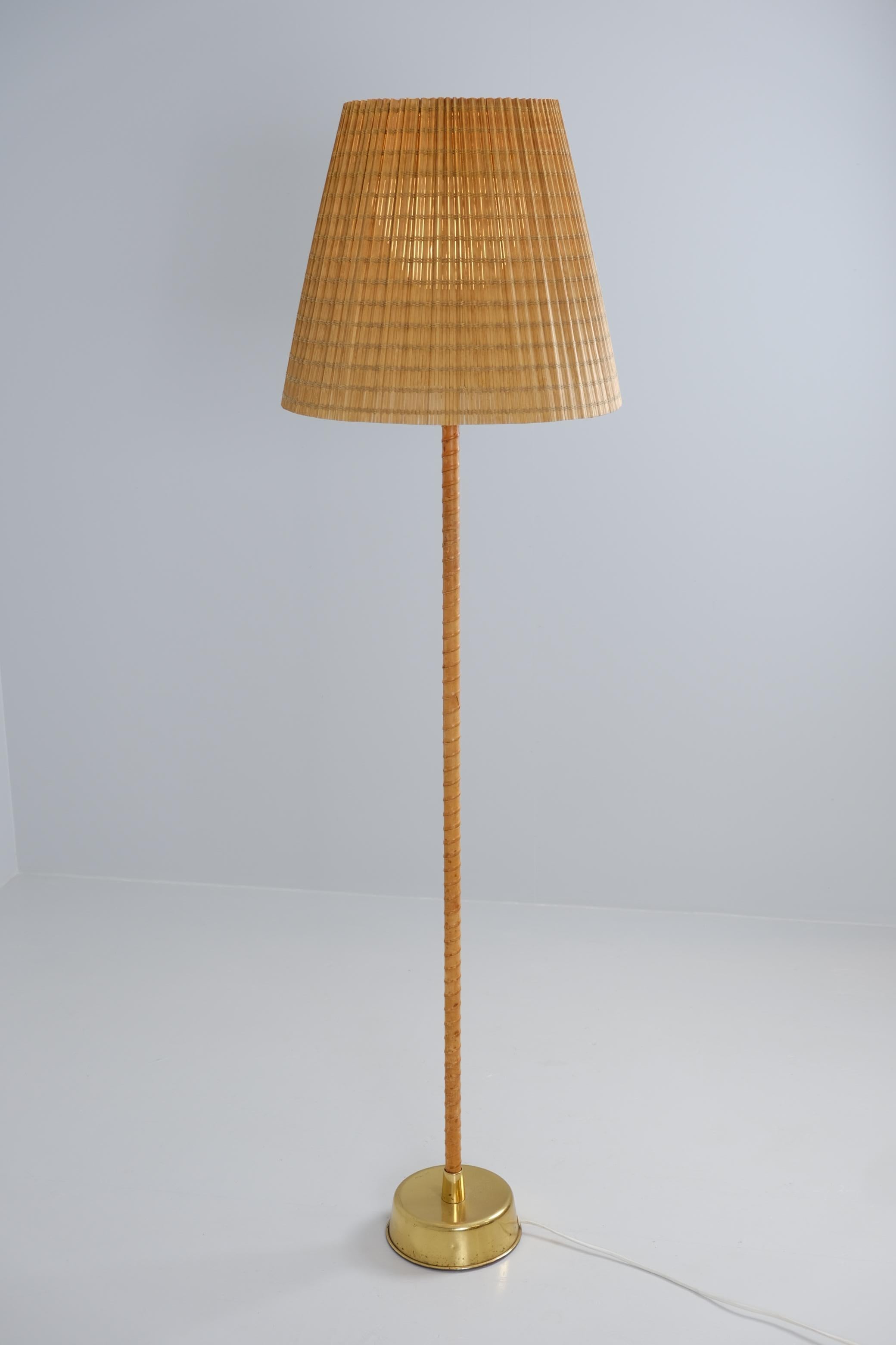Una preciosa lámpara de pie Ihanne de Lisa Johansson-Papé, fabricada en latón, cuero y acrílico con un difusor de ratán, que desprende un precioso encanto patinado. Esta lámpara complementa sin esfuerzo los interiores de mediados de siglo, así como