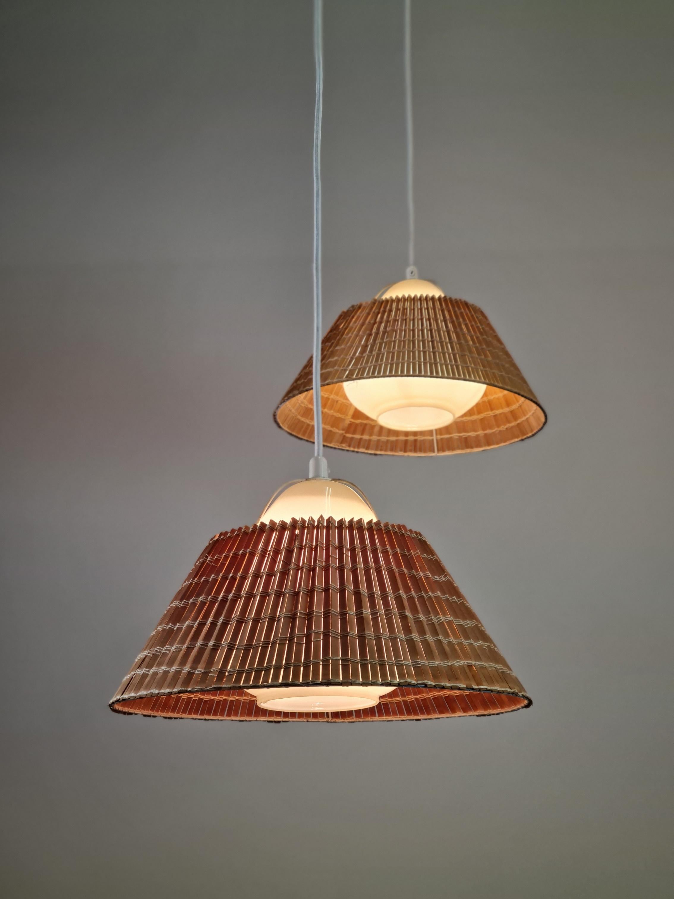 A lovely pair of Lisa Johansson-Papé ceiling lamps from the 1940s. A beautiful organic design of pear shaped mouth blown opal glass with the original rattan shade. As the lamps hand freely and supported by the electric wire, these pendants are