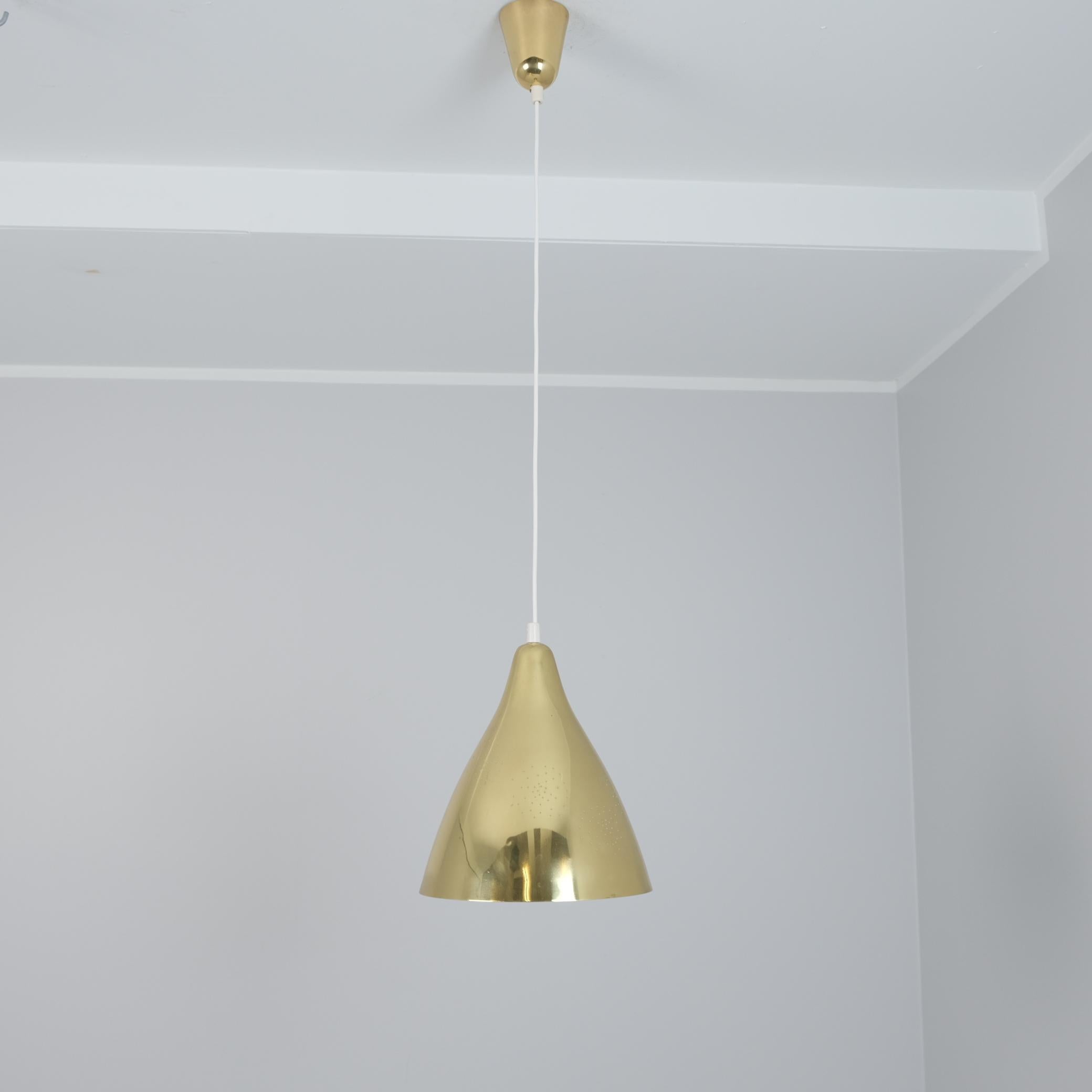Una bellissima lampada da soffitto modello 61-314 disegnata da Lisa Johansson-Pape e prodotta da Orno negli anni Cinquanta. Questa lampada è in ottone pieno, con un paralume traforato pieno di piccoli puntini nel suo paternetto circolare che formano