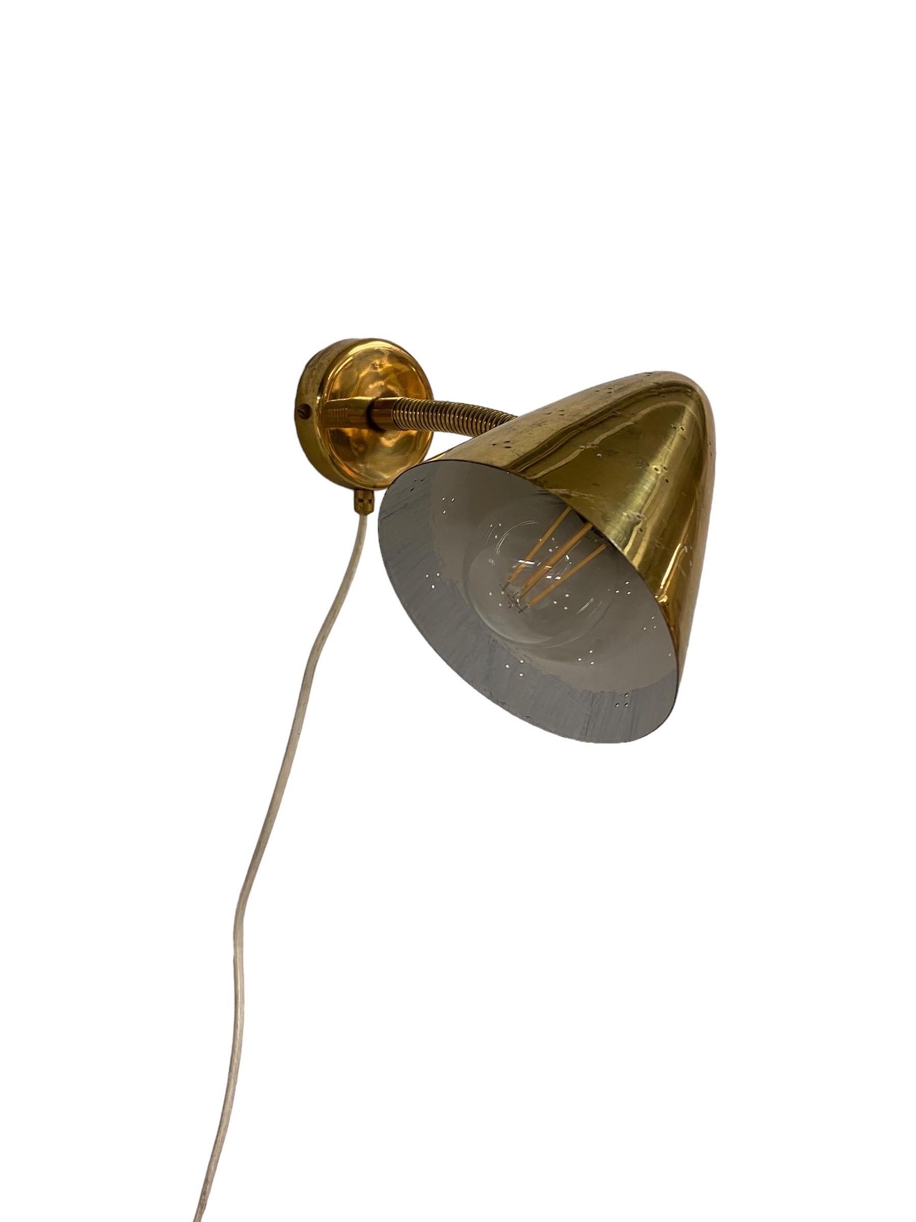 An extremely rare model 50-084 wall sconce, designed by Lisa Johansson-Pape for Orno in the 1950s in Finland. This exact one is a more rare version of the model, which usually comes in painted metal. The perforations in the brass shade of this lamp