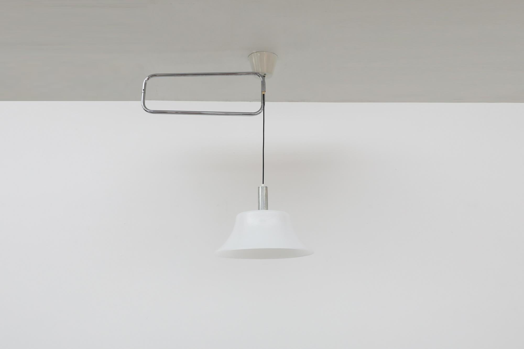 La lampada da soffitto snodabile cromata nello stile di Lisa Johansson-Pape per Orno presenta un caratteristico paralume a cappello in plexi bianco e un sistema di bracci rettangolari cromati. Il baldacchino da soffitto in metallo smaltato bianco