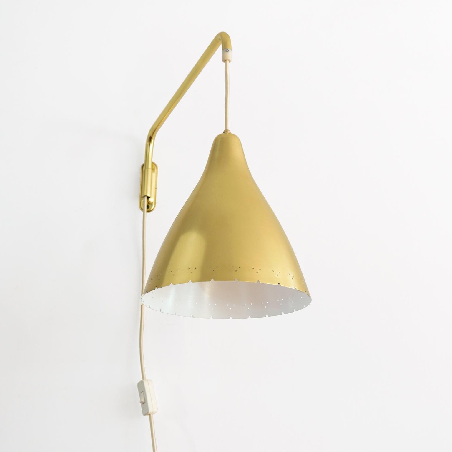 Lisa Johansson-Pape, Scandinavian Modern wall mounted swing arm lamp with pierced lacquered brass shade on a swing arm. Newly restored, re-polished and lacquered brass, the shade may be raised and lowered. The lamp has been wired for the USA with