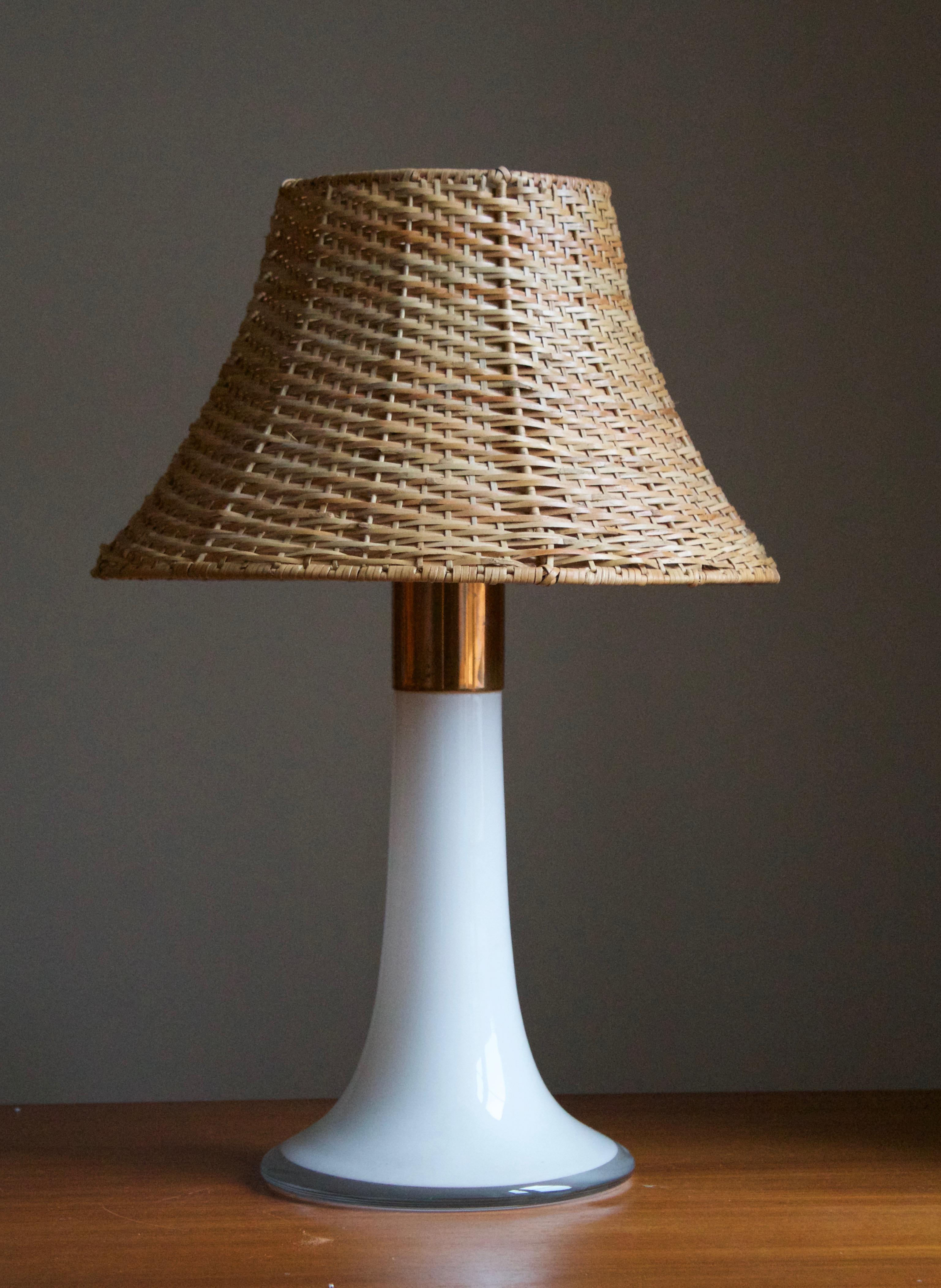 A table lamp, designed by Lisa Johansson-Pape in 1954. Produced in the 1960s by Oy Stockmann-Ornö AB. Executed in opaque glass and Copper.

Stated measurements excluding lampshade. Upon request assorted vintage rattan lampshade illustrated can be