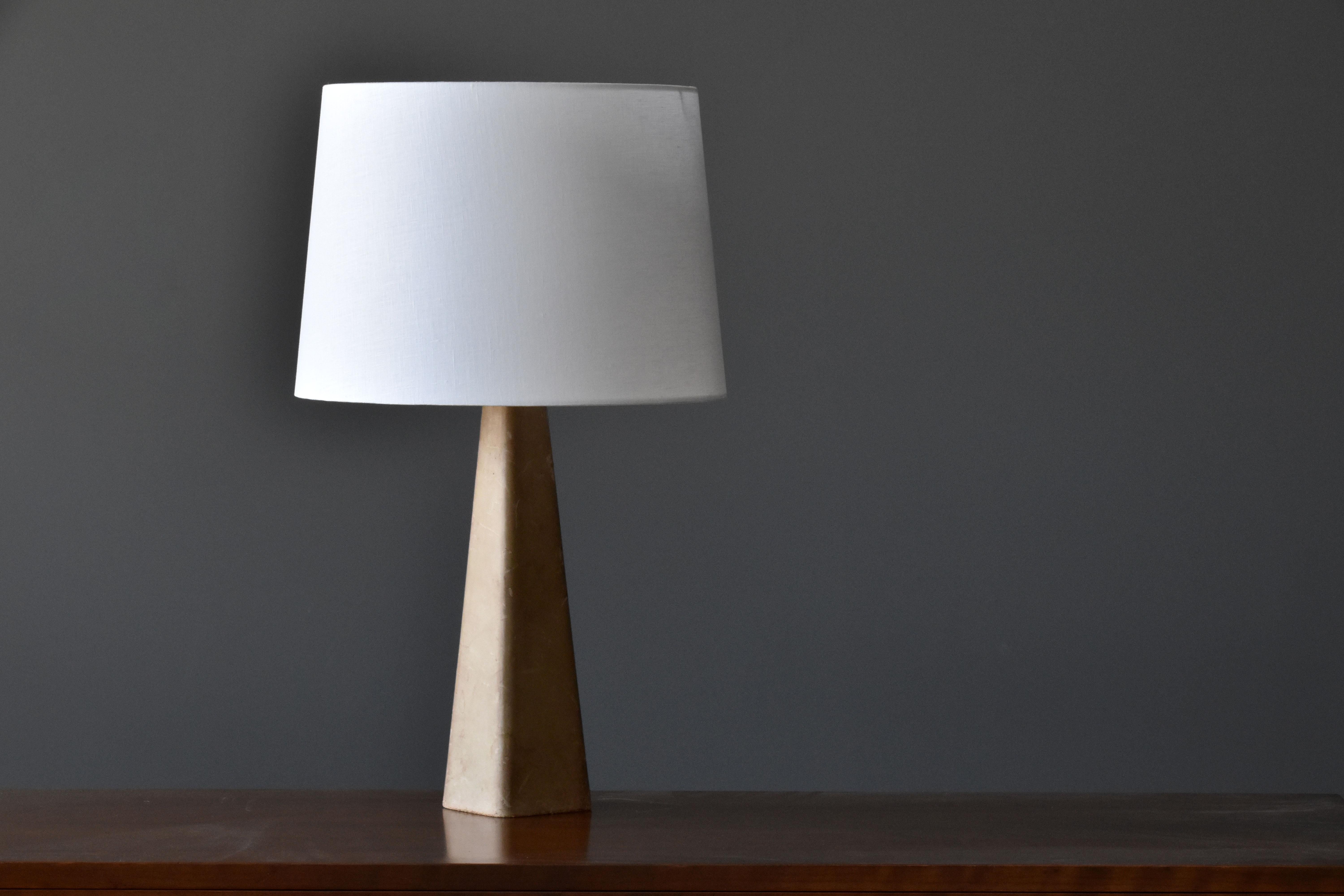 A table lamp designed by Lisa Johansson-Pape. Produced by Ornö, Finland in the 1960s. 

Made of a solid block of wood covered in leather, fitted with a brass neck and fabric screen. 

Other contemporary Scandinavian lighting designers include