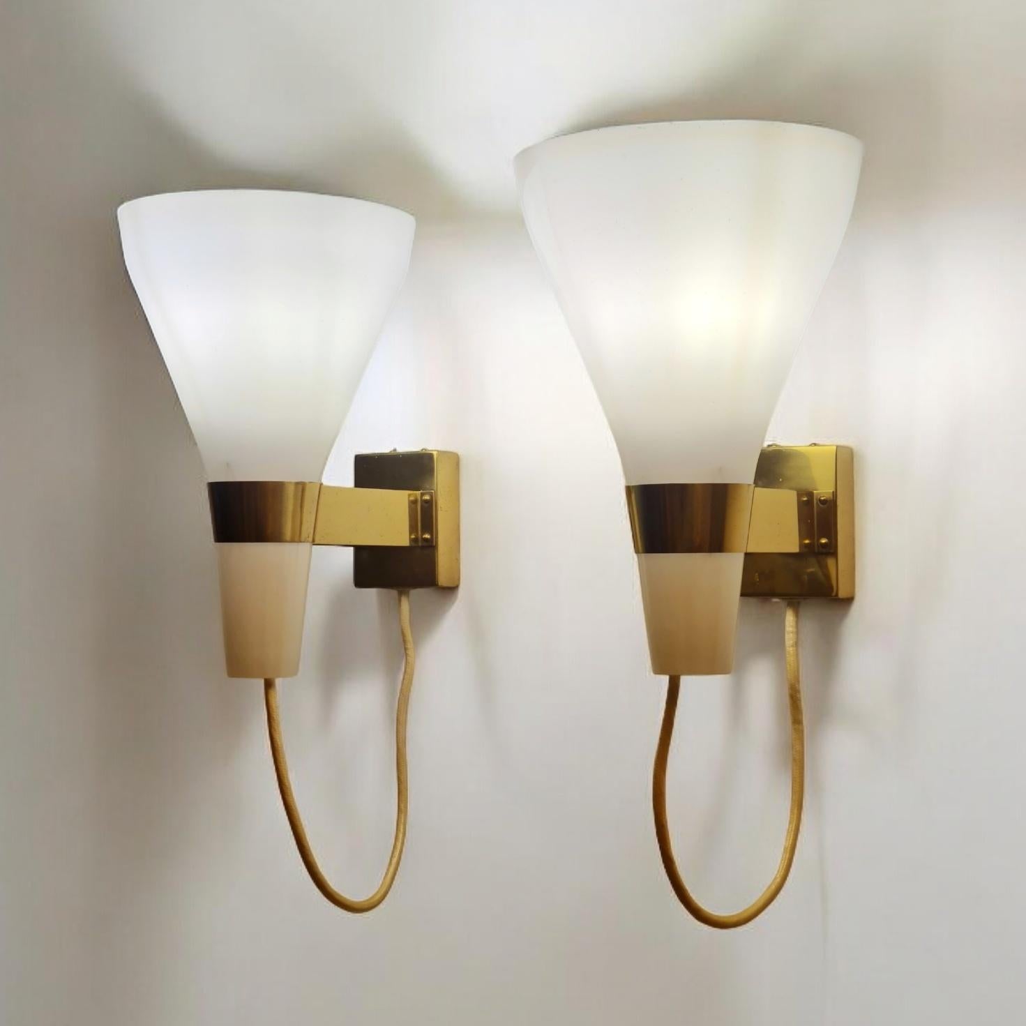 A vintage 1950s pair of wall lamps model 50-090 by Finnish designer Lisa Johansson-Pape for Orno. A minimalist par consisting of solid brass arms holding lyster champagne colour opaline glass. The shades are rare and more extravagant than the usual