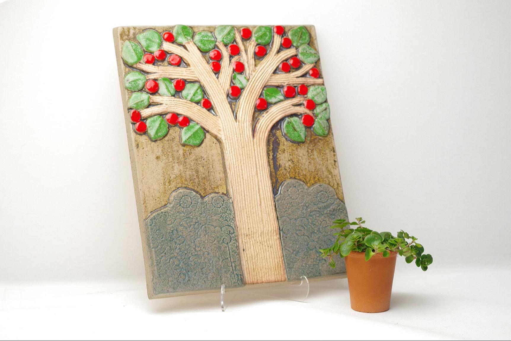 Product Description:
This tile of an apple tree by Lisa Larson is very rare. There exists a more common version of this tile which has a man and woman sitting in front of the tree, this tile however does not have the couple on it. Although the