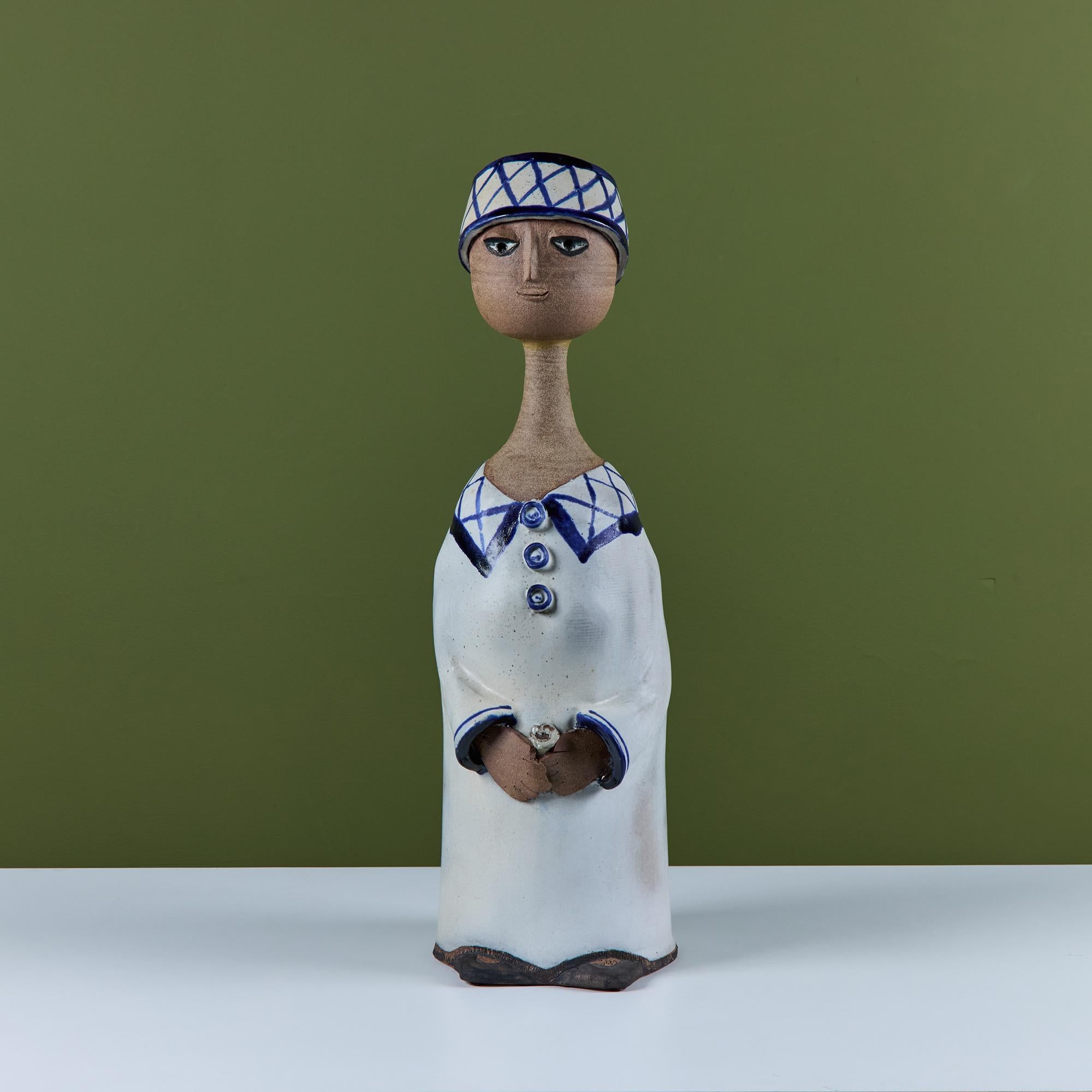 Ceramic glazed sculpture of a boy in the style of Lisa Larson. This figure features a boy with a glazed cream and blue hat with matching outfit. His hands carry a small flower.

Dimensions
8.75” width x 9.5