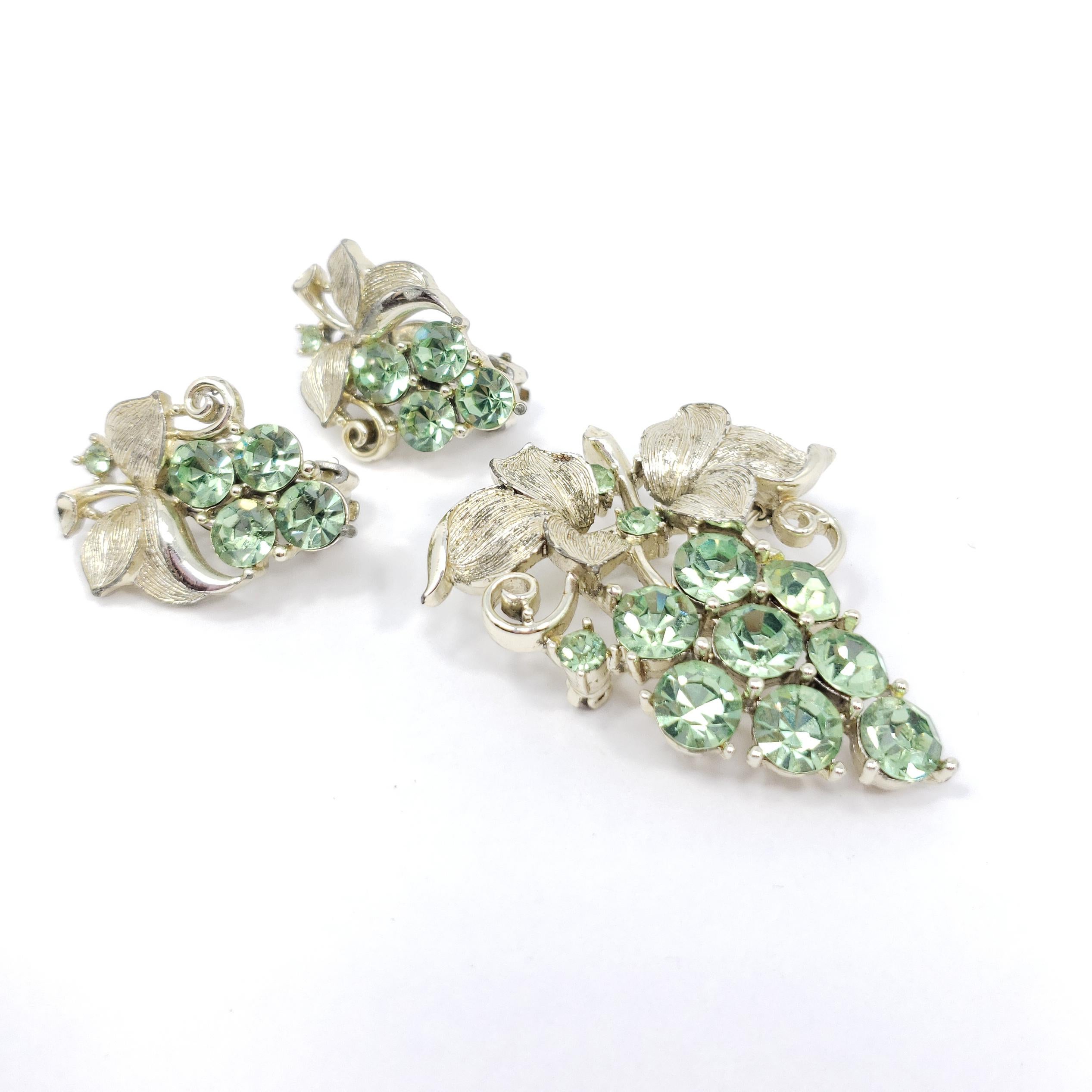 A sophisticated set from Lisner, featuring white gold-tone leaves with peridot green fruit clusters. Includes a single pin brooch and a pair of clip-on earrings.

Gold-tone. Vintage, 20th century.

Brooch dimensions: 2