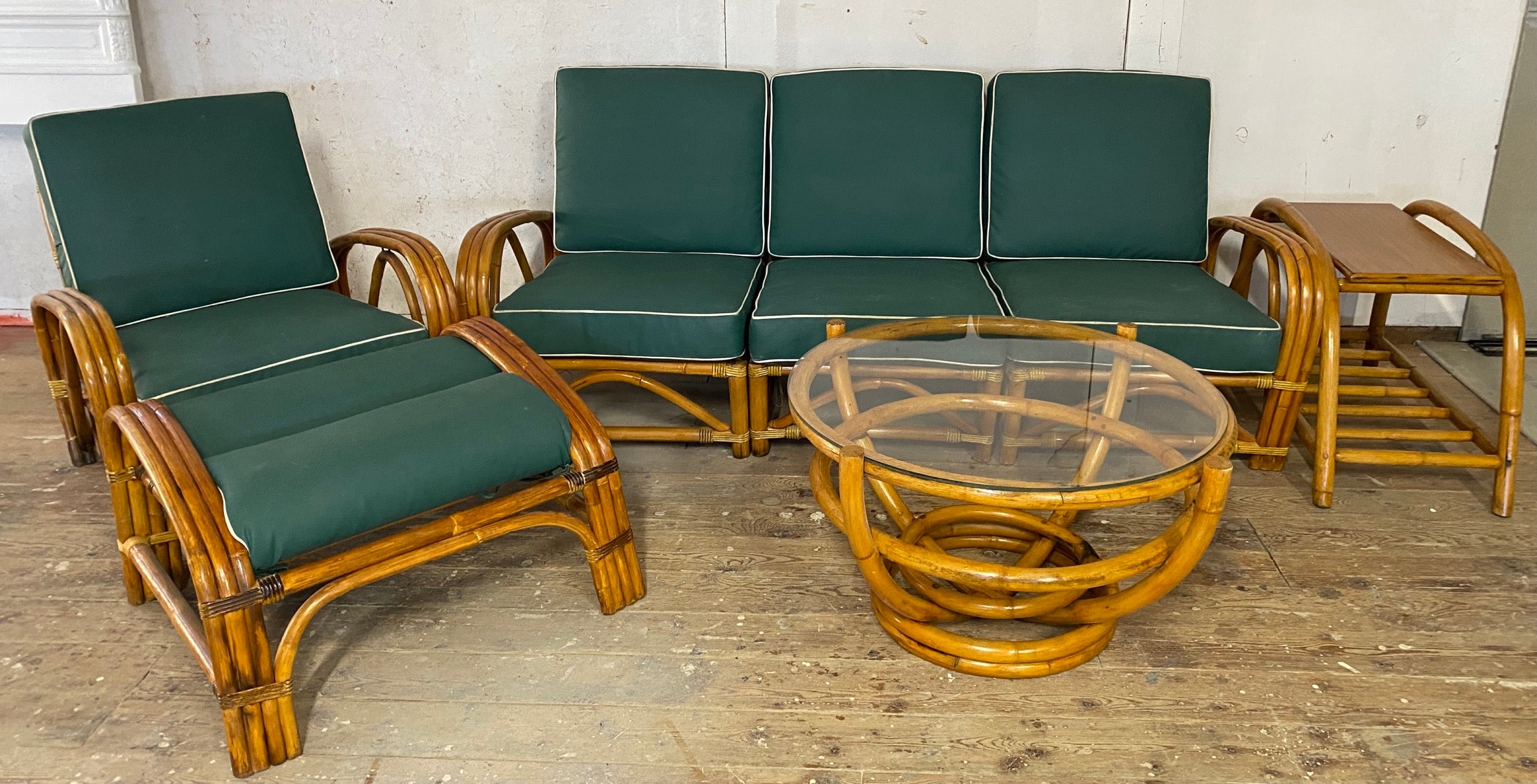Restored 3 strand Paul Frankl style 6 piece rattan living room seating set consisting of 3 separated seat sofa, arm club chair with matching ottoman, side table, 2 tier corner table and round glass top coffee table. Cushions covered in vintage vinyl