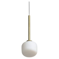 Lita Lighting è una lampada a sospensione in ottone spazzolato con vetro opalino a cilindro di Nuumbra.