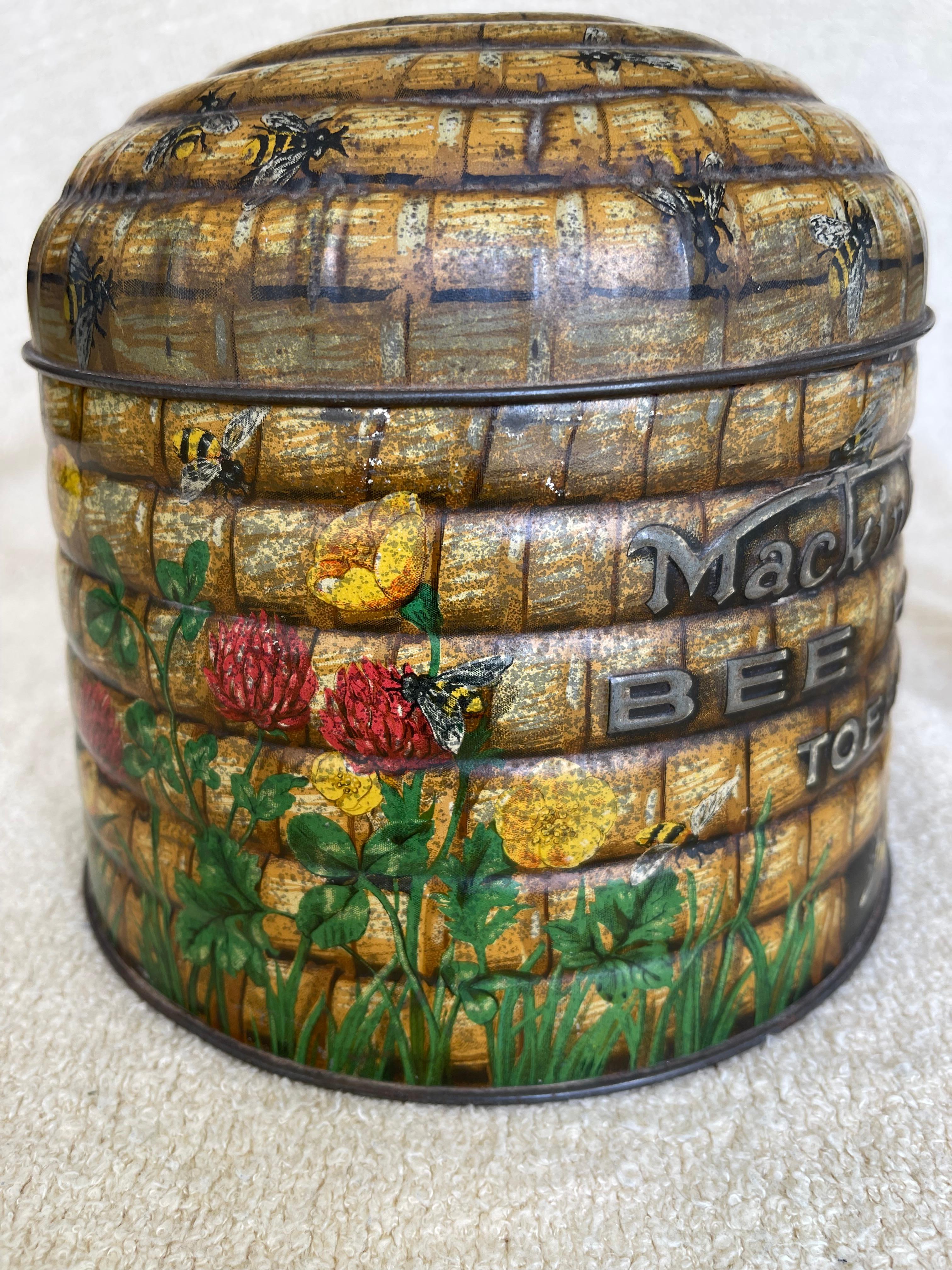  This good size tin is English and made somewhere in the art deco period, 1920's. Originally it held toffee, but certainly can be used for anything. The beauty is in the colorful and unusual graphics. The shape is in a beehive and there are bees and