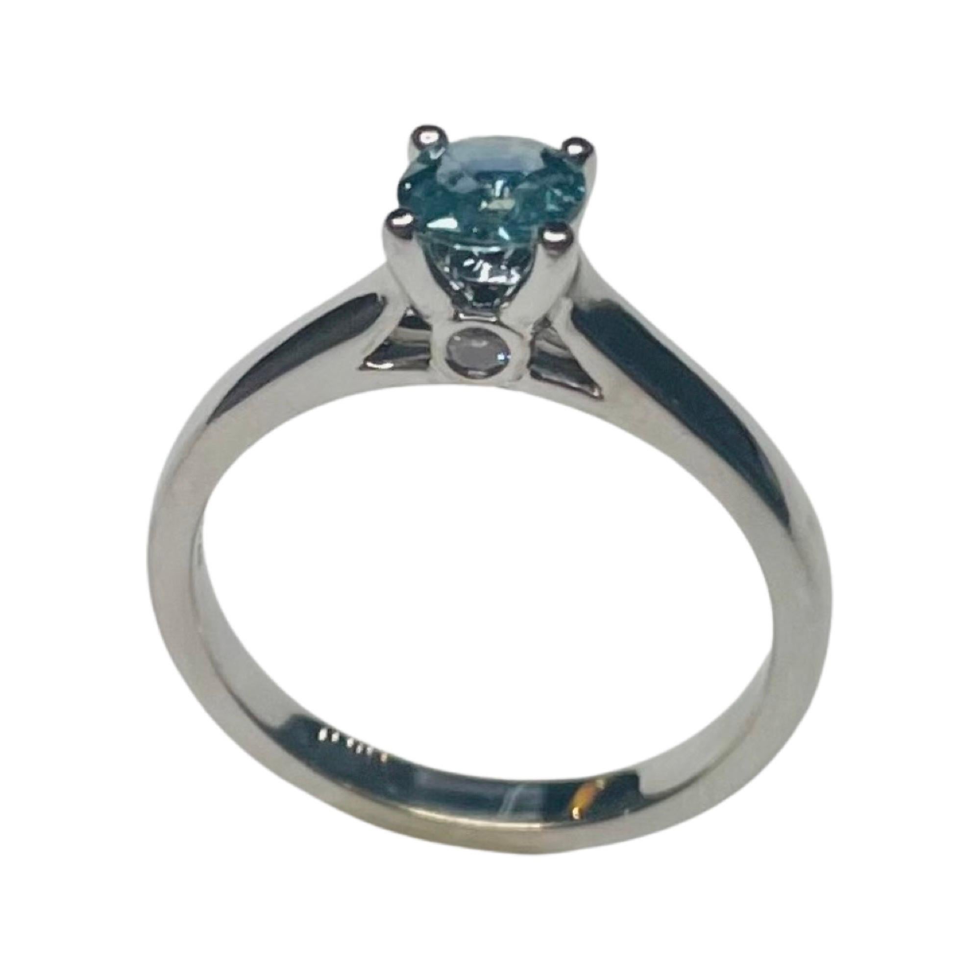 Lithos 14K White Gold Montana Sapphire and Diamond Ring. The prong set center Montana sapphire is 0.50 carats. There are 2 full cut round brilliant diamonds bezel set on each side of the center head. They are VS Clarity and G color. The total