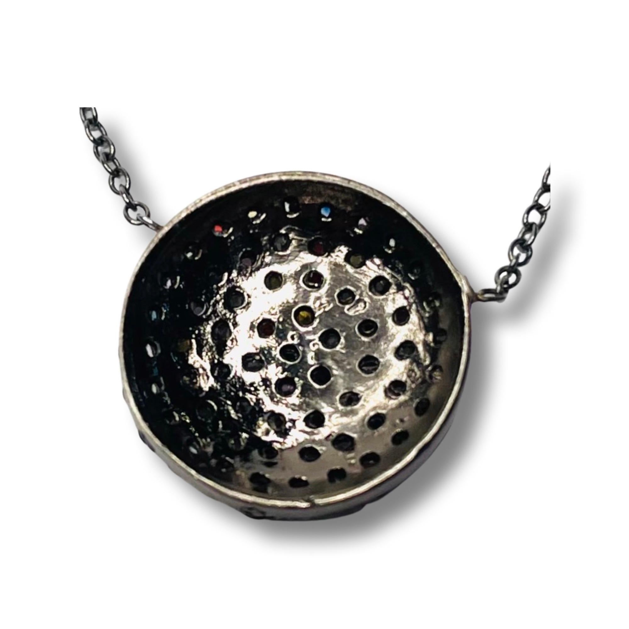Lithos Sterling Silver Multi Colored Sapphire Necklace Black Rhodium. The center is a 15.0 mm disc. It is pave set with multicolored natural sapphires.  It is 16 inches in length with a spring ring closure. 
500-85-935