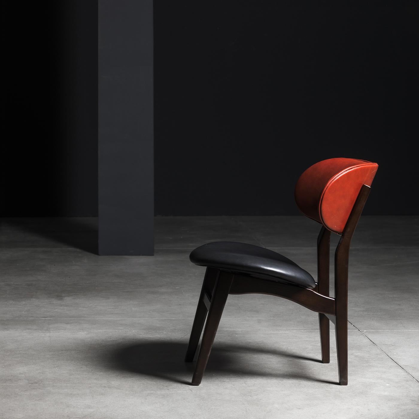 This chair features a sleek, modern silhouette that evokes early 20th century design. Its wooden structure is finished in black, while it features a black leather seat, along with a back in red leather. Its height is 39 cm. The Chelini Firenze