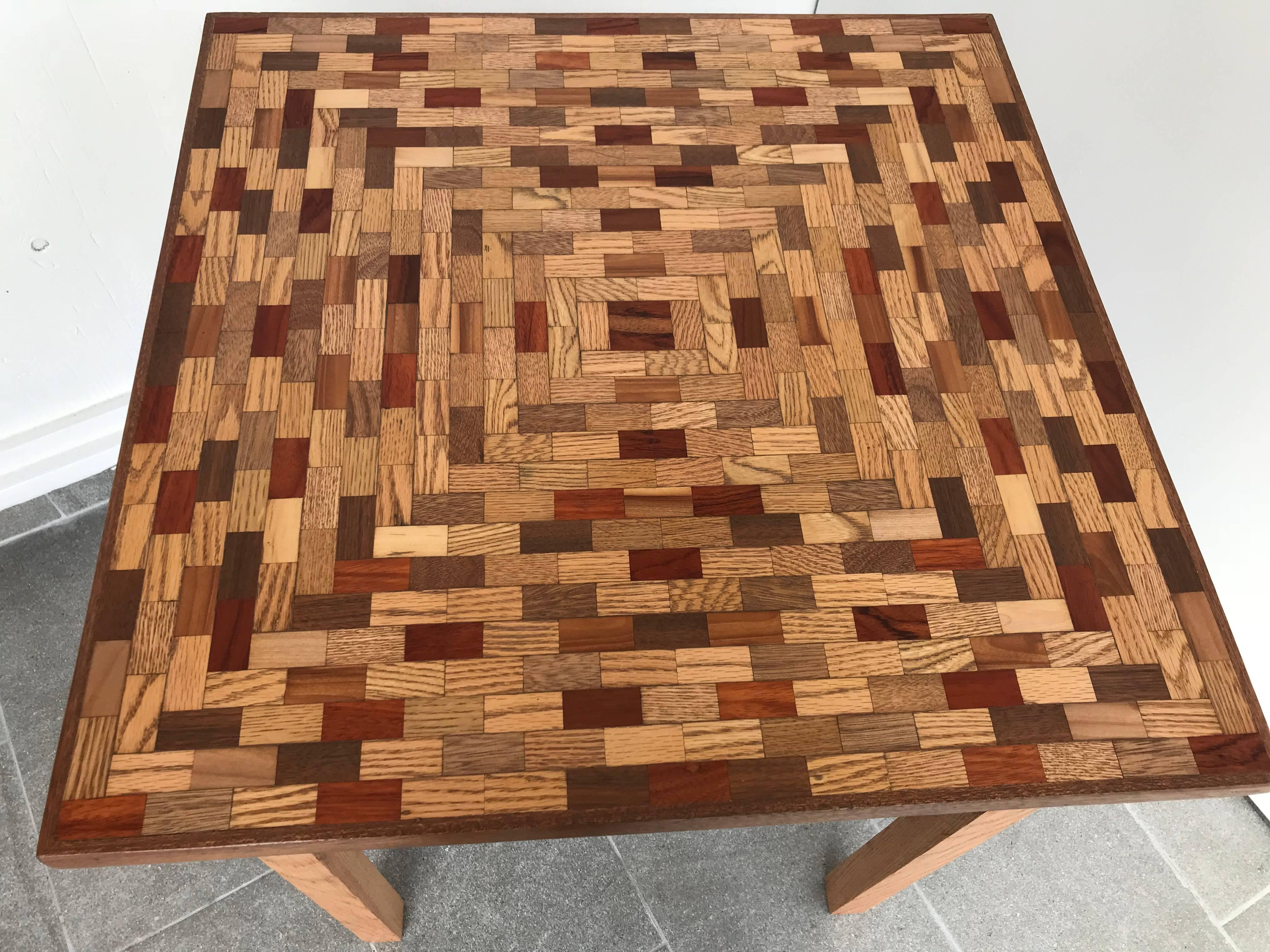 Newly refinished game or dining table has a mixed wood parquet top and oak base there is a small drawer in front with a brass knob.