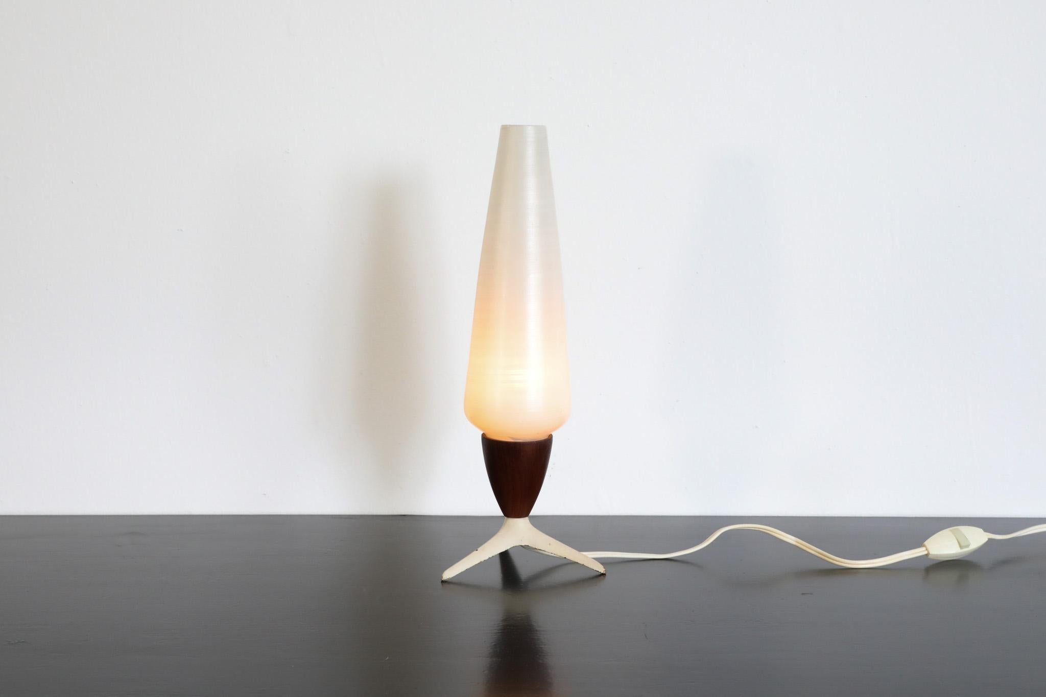 Petite, Mid-Century, table lamp with cigar shaped stripped glass shade. Manufactured by Dutch lighting company Philips. A lovely table lamp with teak base on white enameled metal tri-pod feet that provides a soft, warm light. It is in original