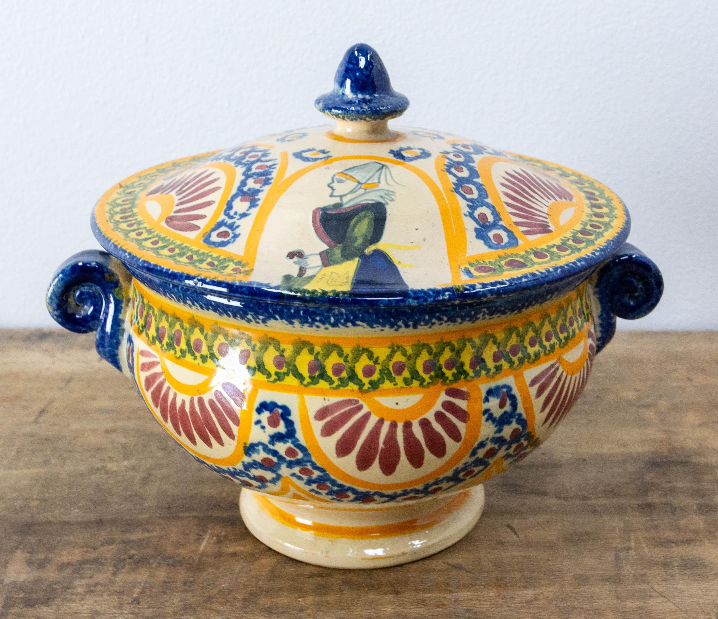 French little tureen from Henriot manufactory in Quimper, Britanny.
The porcelain manufactories exist in Quimper since the 18th century.
Decorated with patterns typical of Britanny, this centerpiece or vide poche is décorated with a woman in