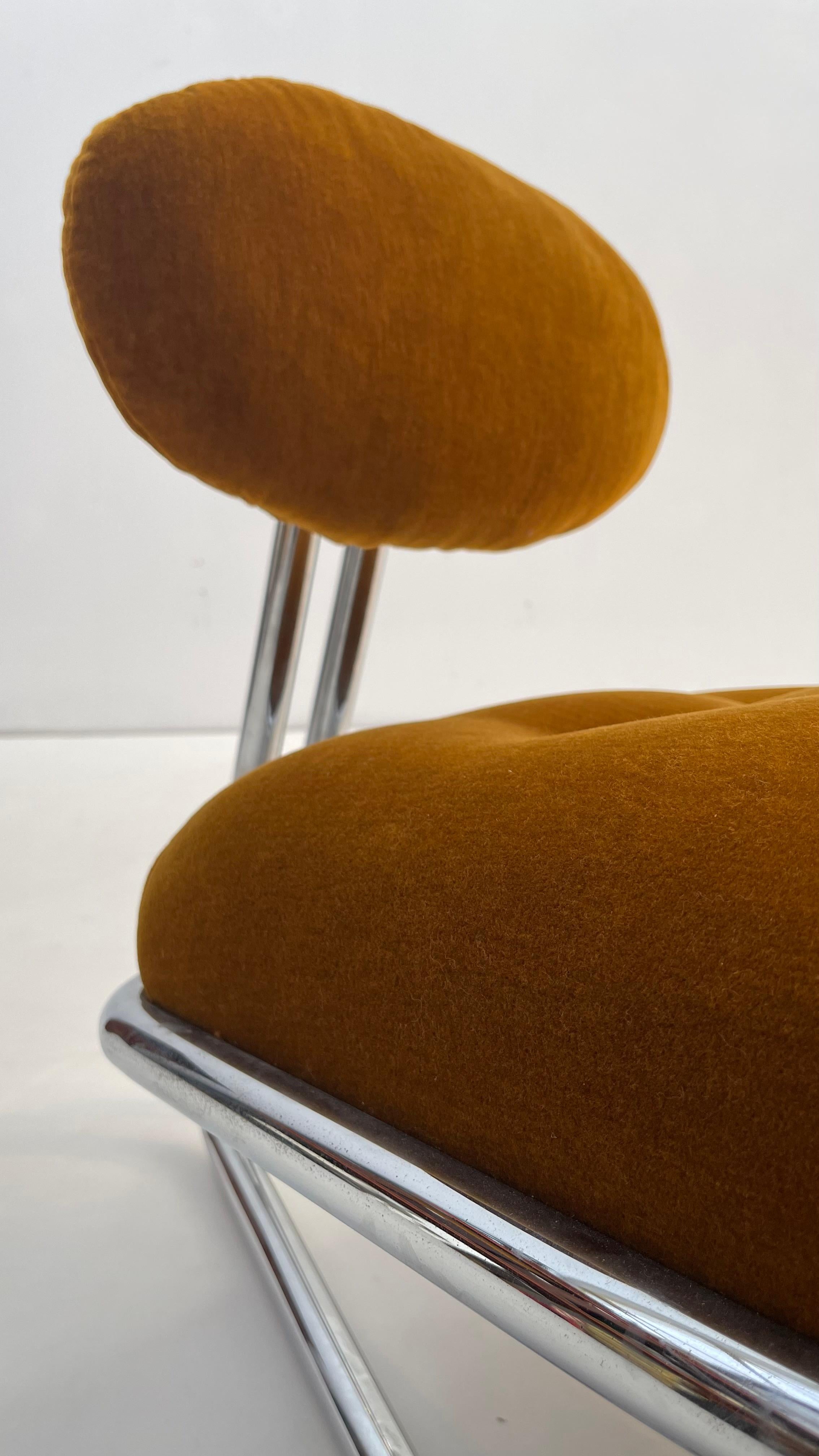 This very confortable little lounge chair in shaved rusty/orange velvet is a bold statetement to your modern or mi-century interior style. 

Plated in chrome, the tubular frame gives a levitating impression to the chair giving to your interior a