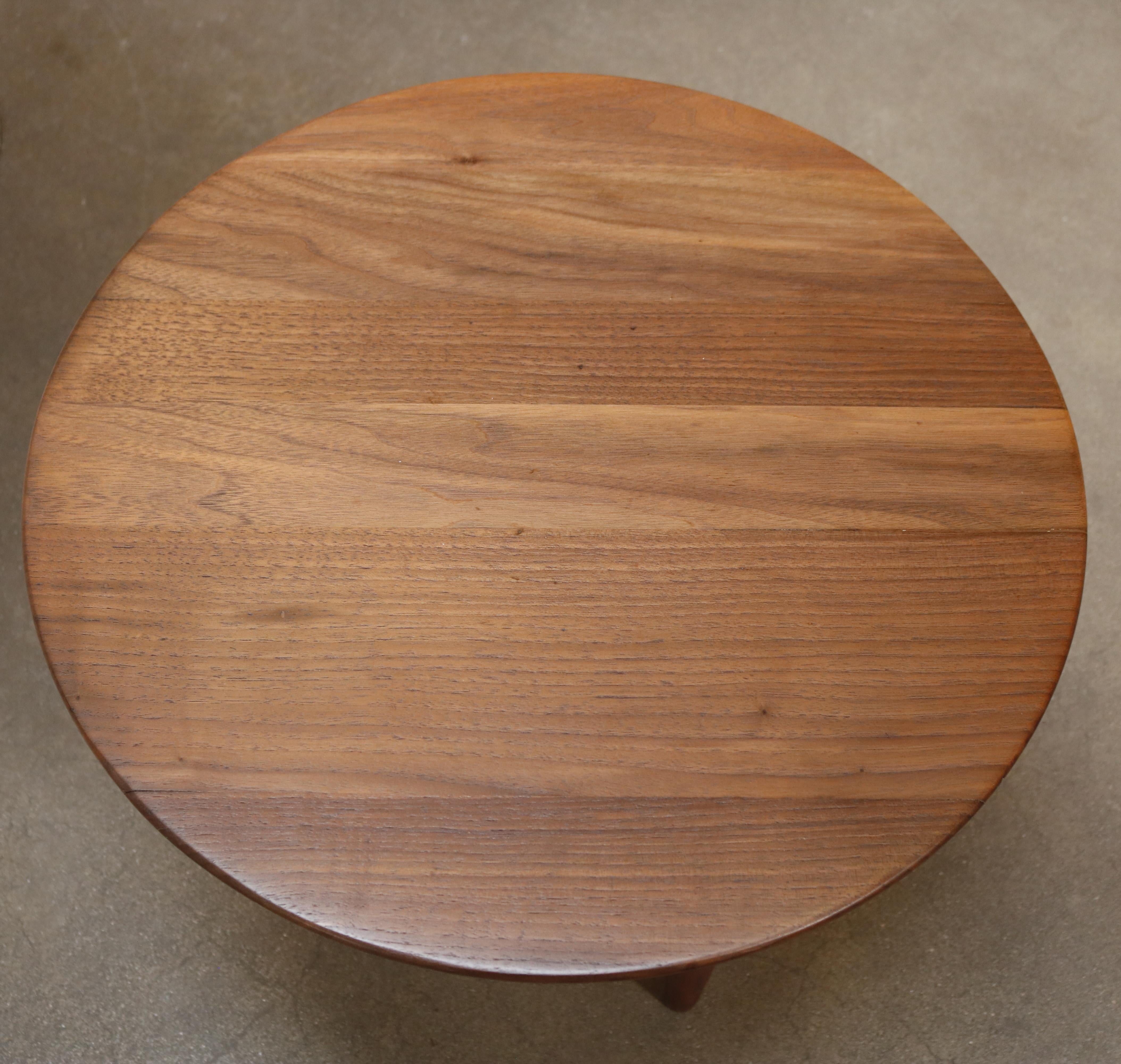 A petite, solid walnut circular gueridon with three pointy table legs.