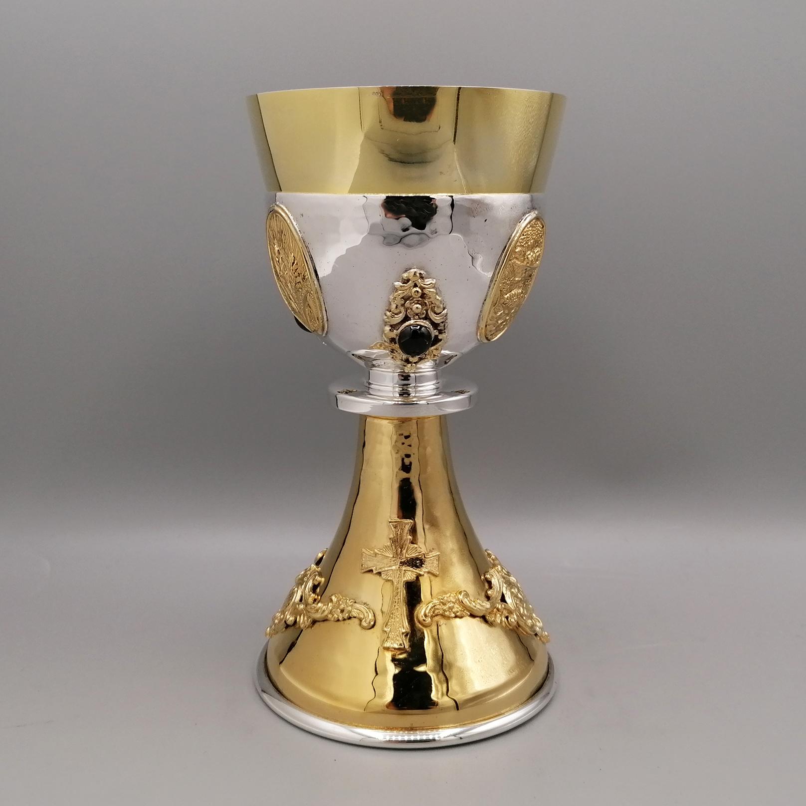 Liturgical chalice in two-tone 800 solid silver with semiprecious stones.
The body of the liturgical chalice is slightly hammered.
The conical stem was completely gilded and two friezes and two baroque crosses were subsequently applied, made with