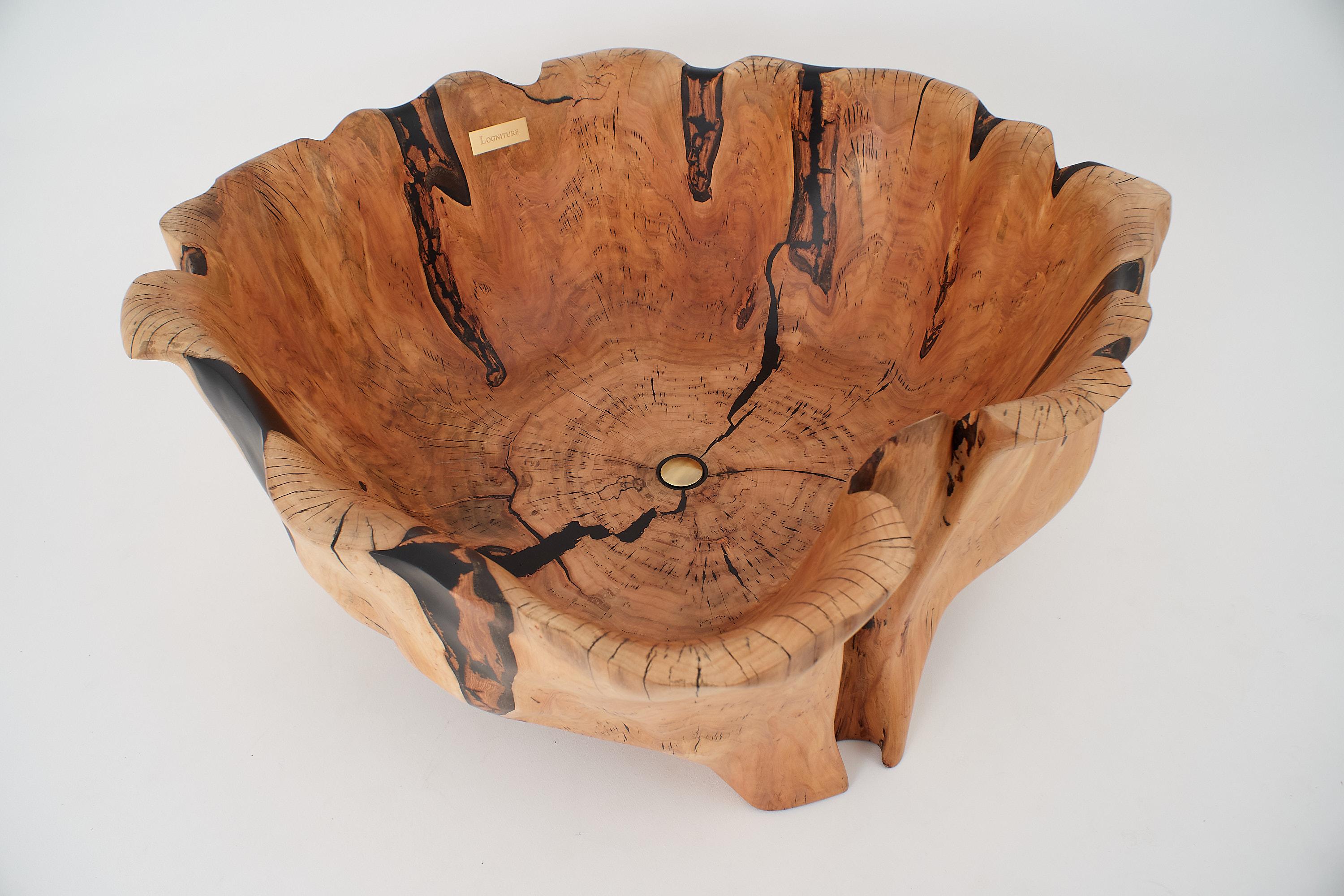 This sculptural bathtub is a one-of-a-kind piece carved entirely by hand from a single massive hardwood trunk. Its form flows outward like a blooming flower, each curve shaped by both the natural growth of the tree and the intuitive carving process.