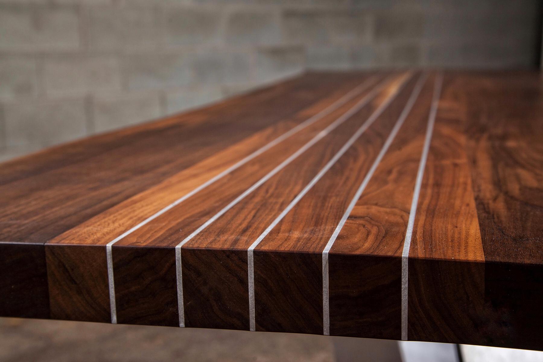 This particular black walnut dining table has aluminium flat inserted in the wood. Five strips for the dining table makes it pop. Our motto, Enhancing wood’s natural beauty has been achieved with this gorgeous live edge black walnut dining table. We