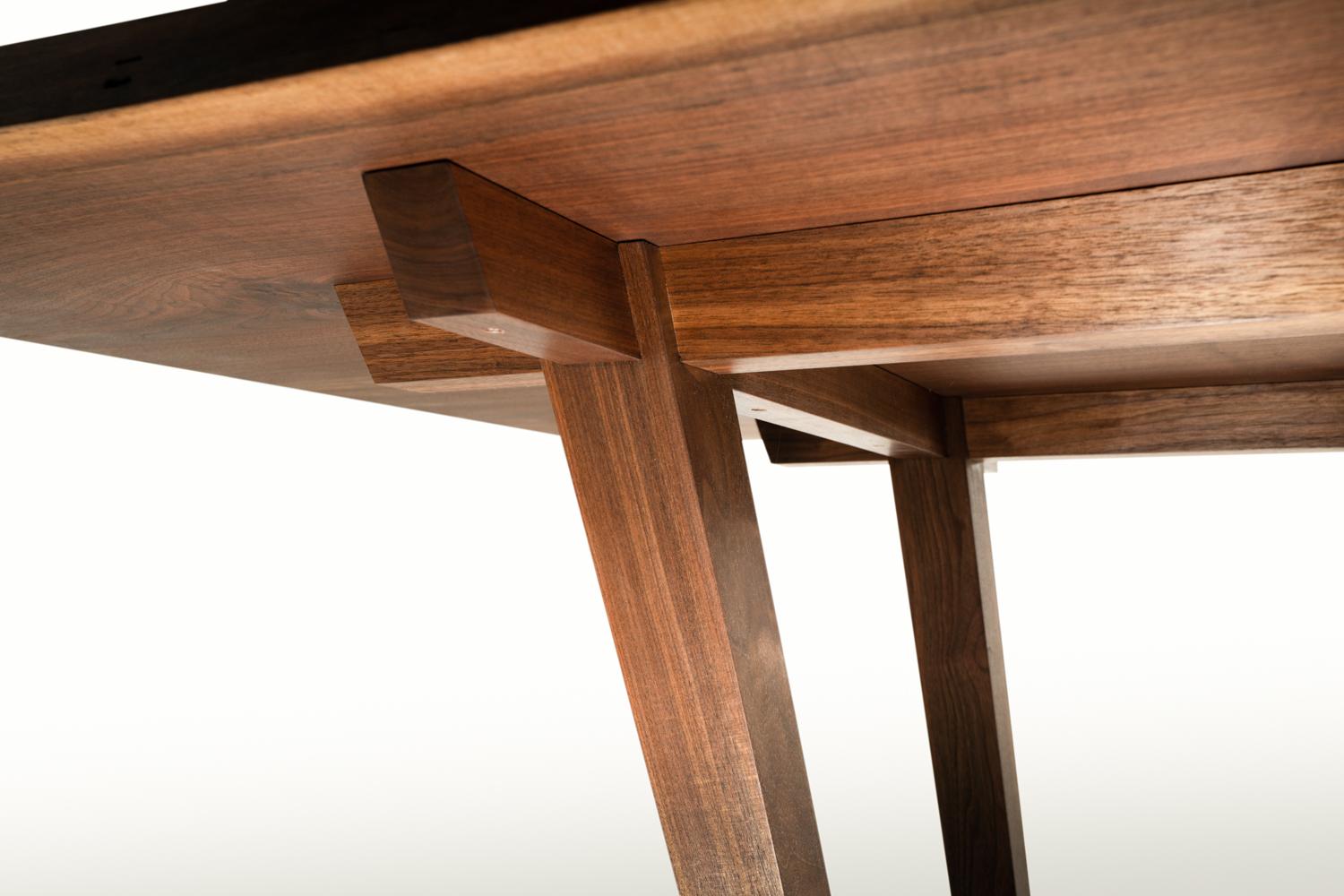 Design original d'une table de salle à manger à pieds évasés, avec un assemblage à angles composés. S'inspirant des éléments traditionnels de la menuiserie japonaise, cette table utilise une menuiserie à emboîtement qui utilise l'angle des pieds