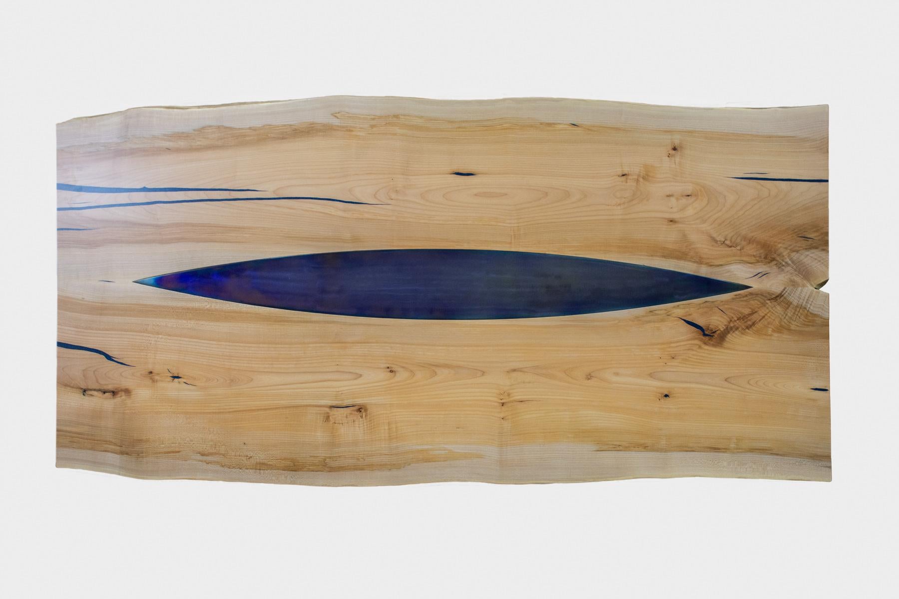 Live Edge dining table made from solid maple with blue steel inlay and gun metal steel base.

Live Edge slabs of solid western maple from he same tree have been paired and joined by a central 'kayak' shaped steel inlay. The steel has been 'blued'