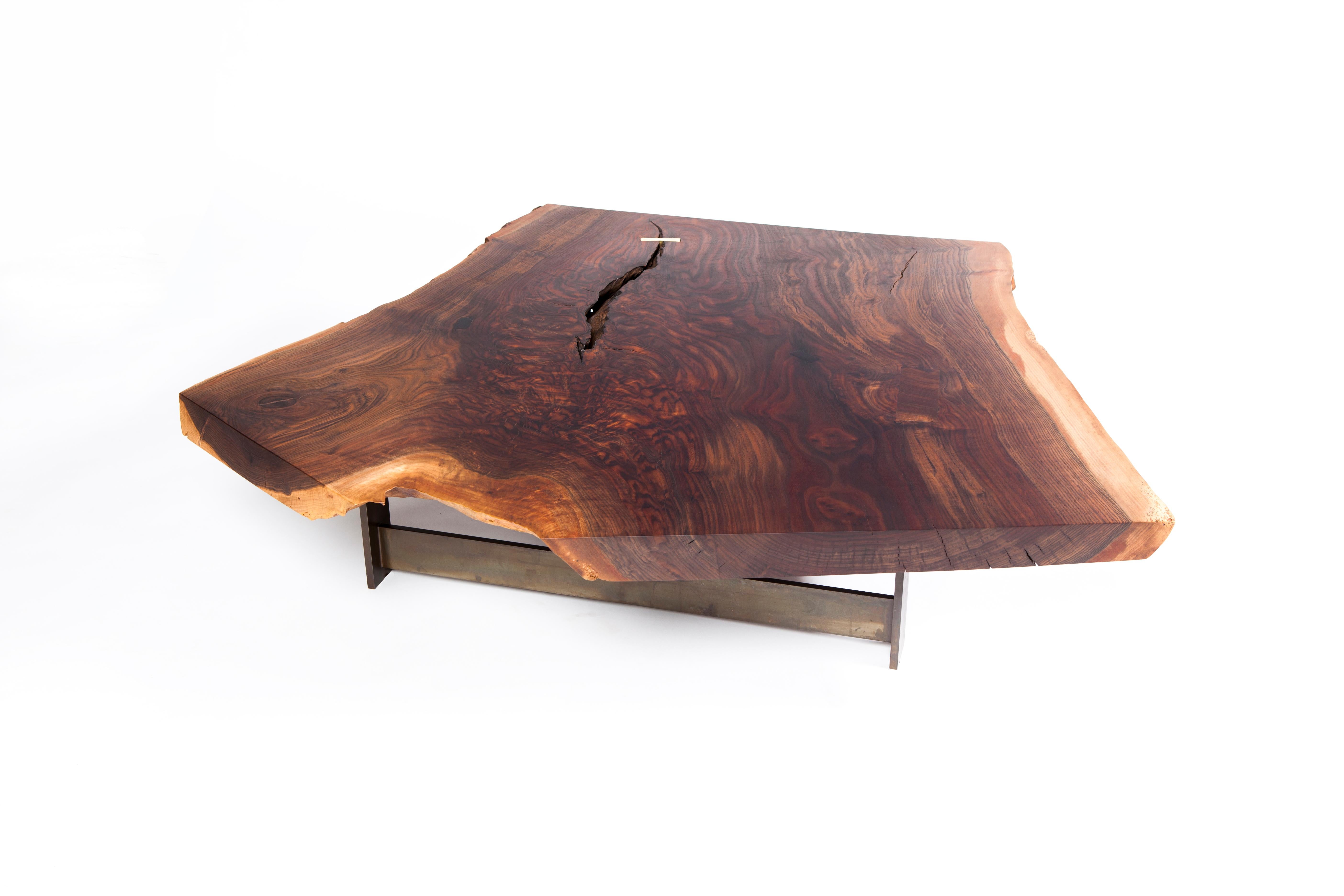 La table basse graft de Taylor Donsker présente un plateau en Y en noyer californien Claro à bords vifs qui repose sur sa base en T en acier patiné caractéristique, ce qui donne l'impression que la dalle flotte sous certains angles. Taylor a ajouté